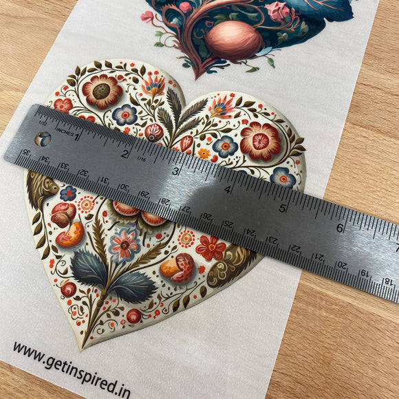 Decorative heart-shaped object with floral patterns and a ruler for scale on a wooden surface.