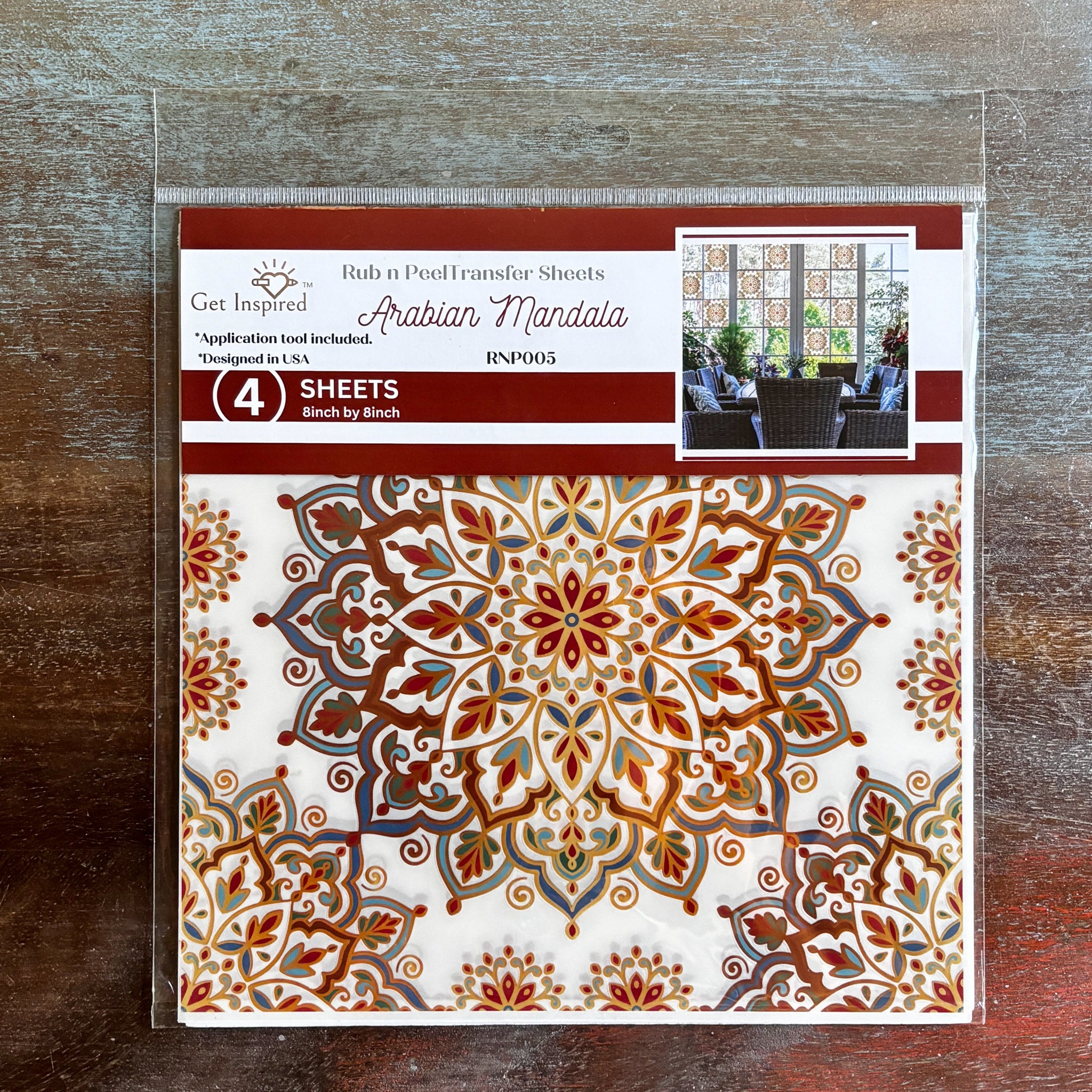 A package of Dadarkar Art's Get Inspired Arabian Mandala transfers is against a dark wood background.