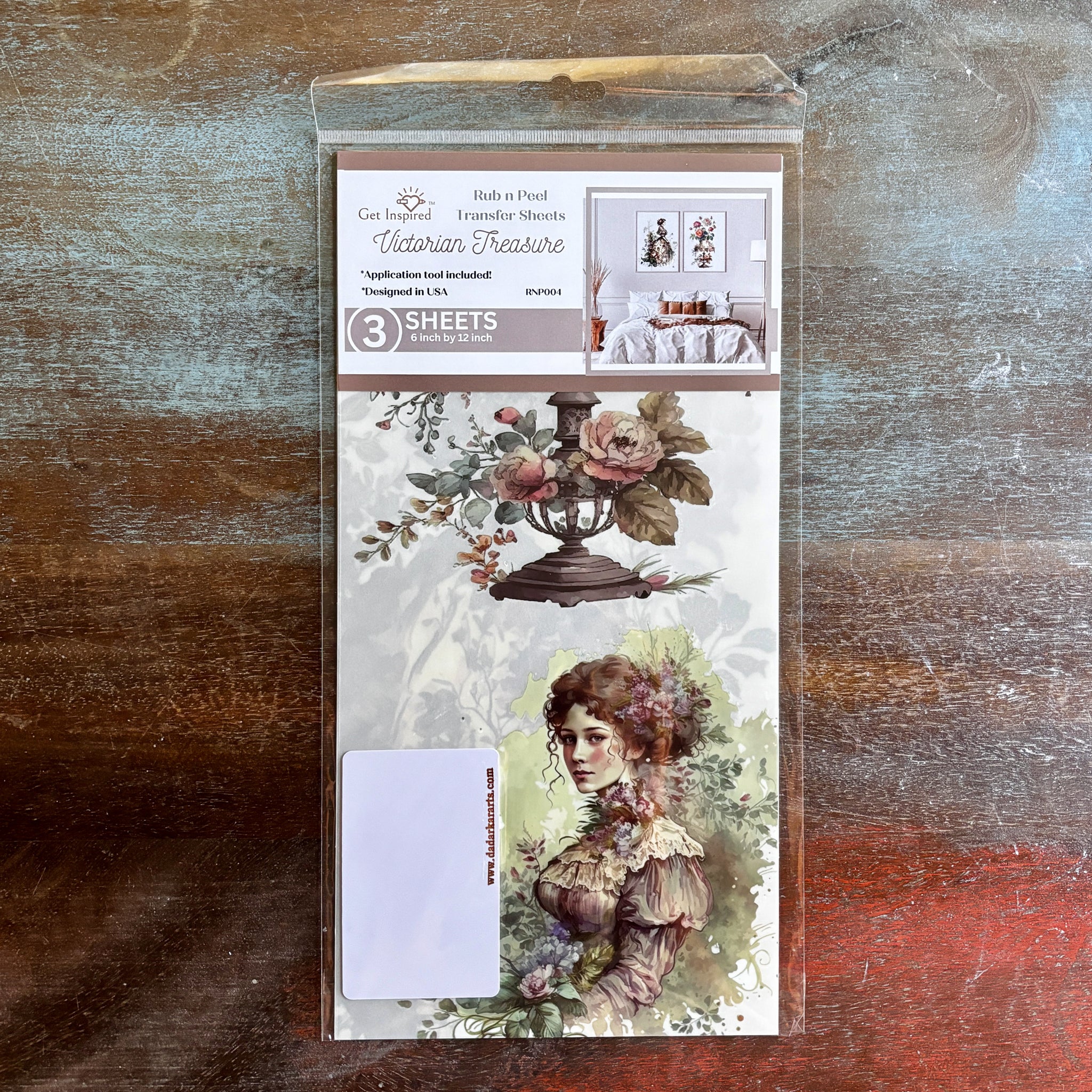 A package of Dadarkar Art's Get Inspired Victorian Treasure rub-on transfers is against a dark wood background.