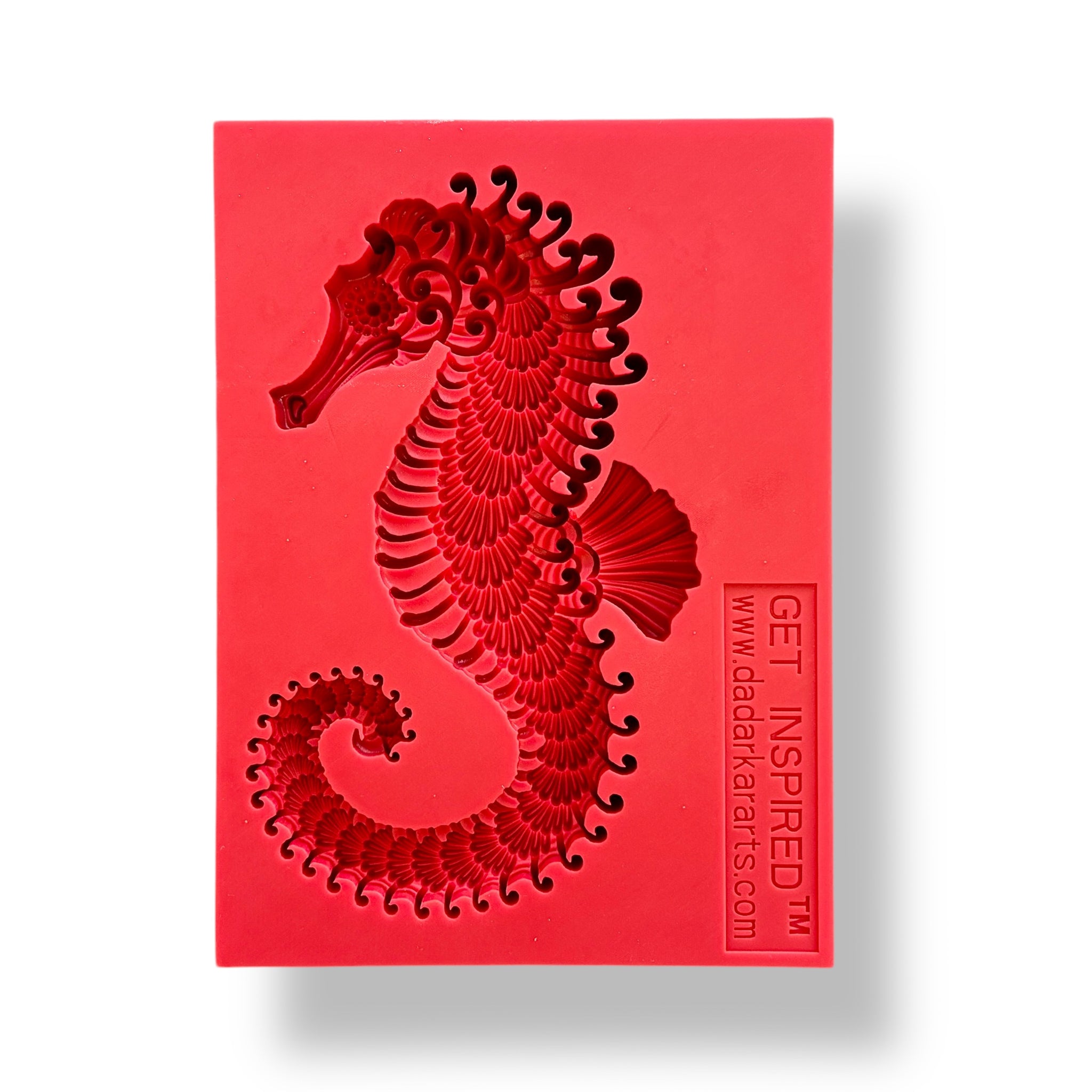 A red silicone mold featuring a seahorse is against a white background.