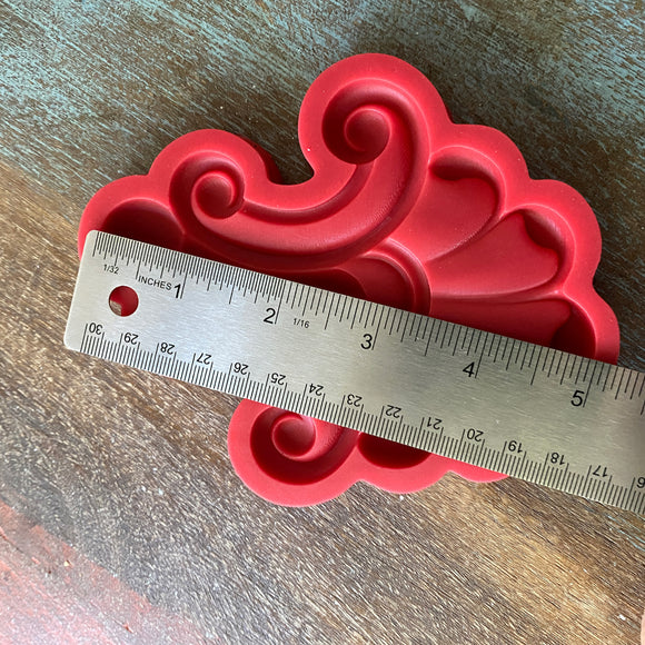 Red decorative silicone mold with a ruler for scale on a wooden surface
