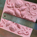 Pink floral silicone mold with a ruler for scale on a wooden surface