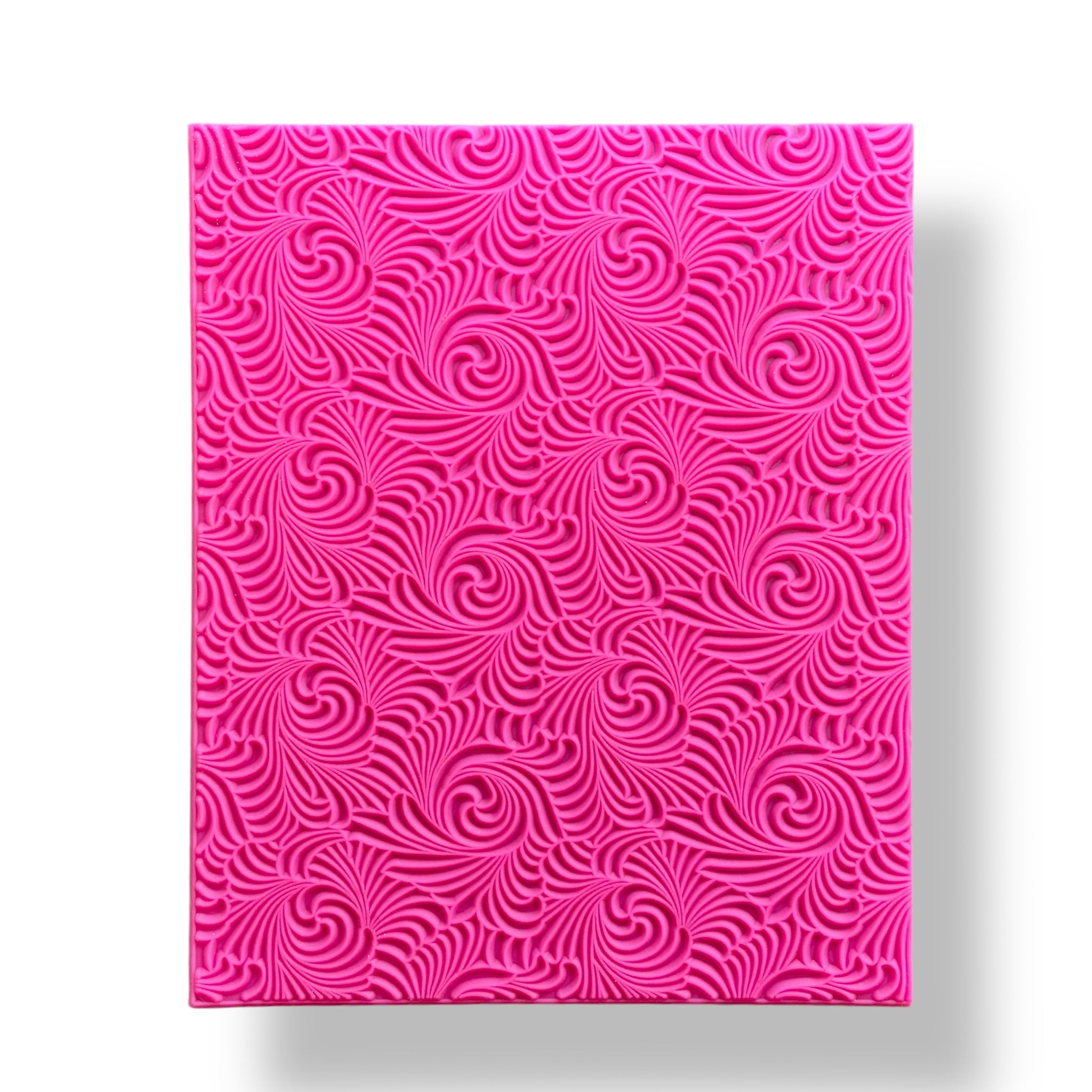 A pink silicone texture sheet with a swirling pattern is against a white background.