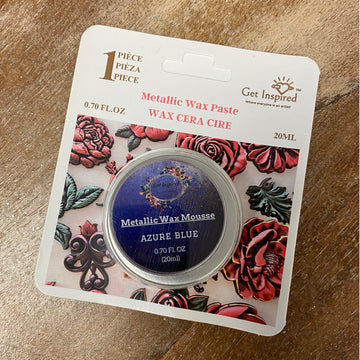 Metallic wax paste packaging with floral design on a wooden surface