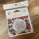 Packaged metallic wax paste with floral design on a wooden surface
