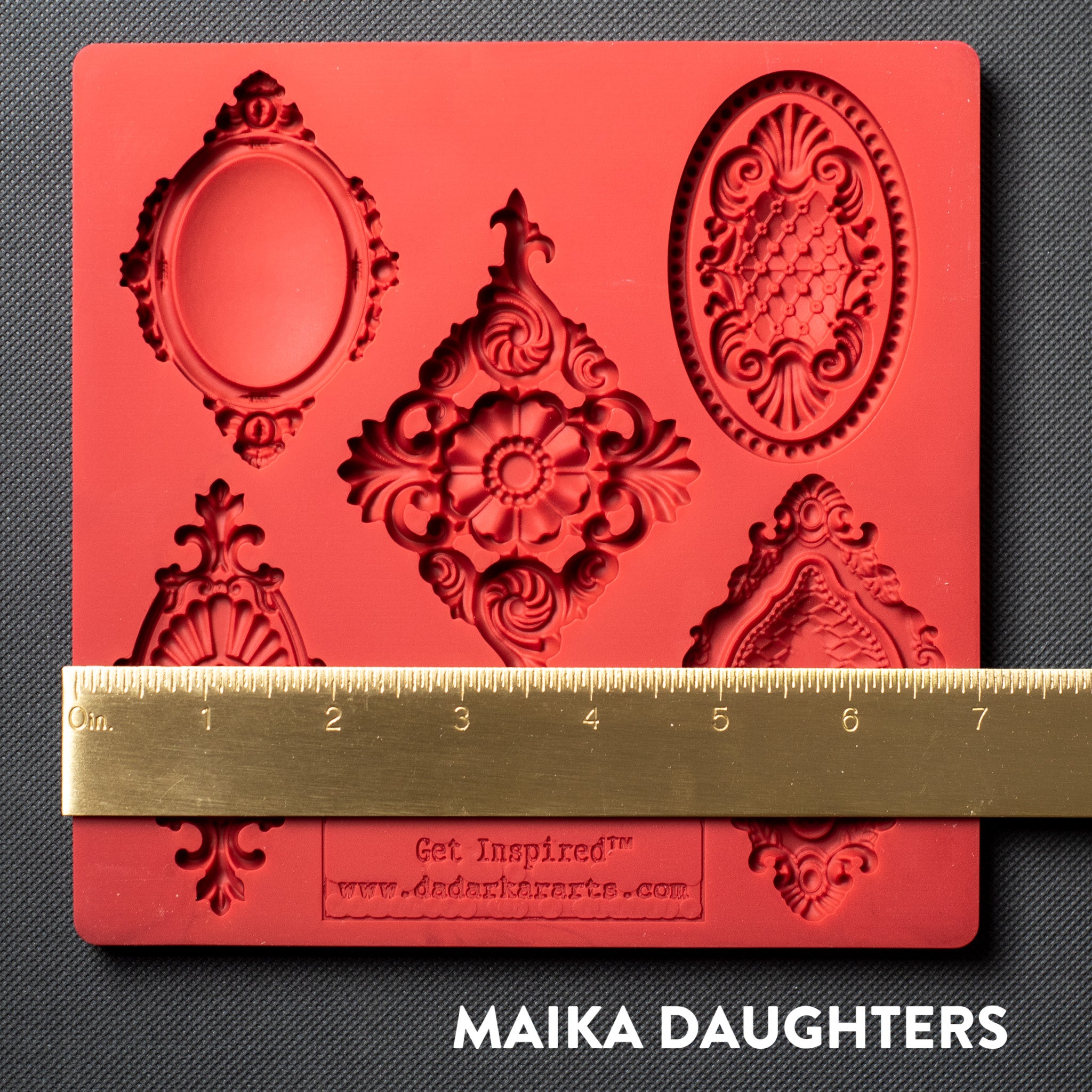 A red silicone mold featuring 5 vintage medallions is against a dark grey background. A gold ruler reading 7 inches in width sits on the mold.