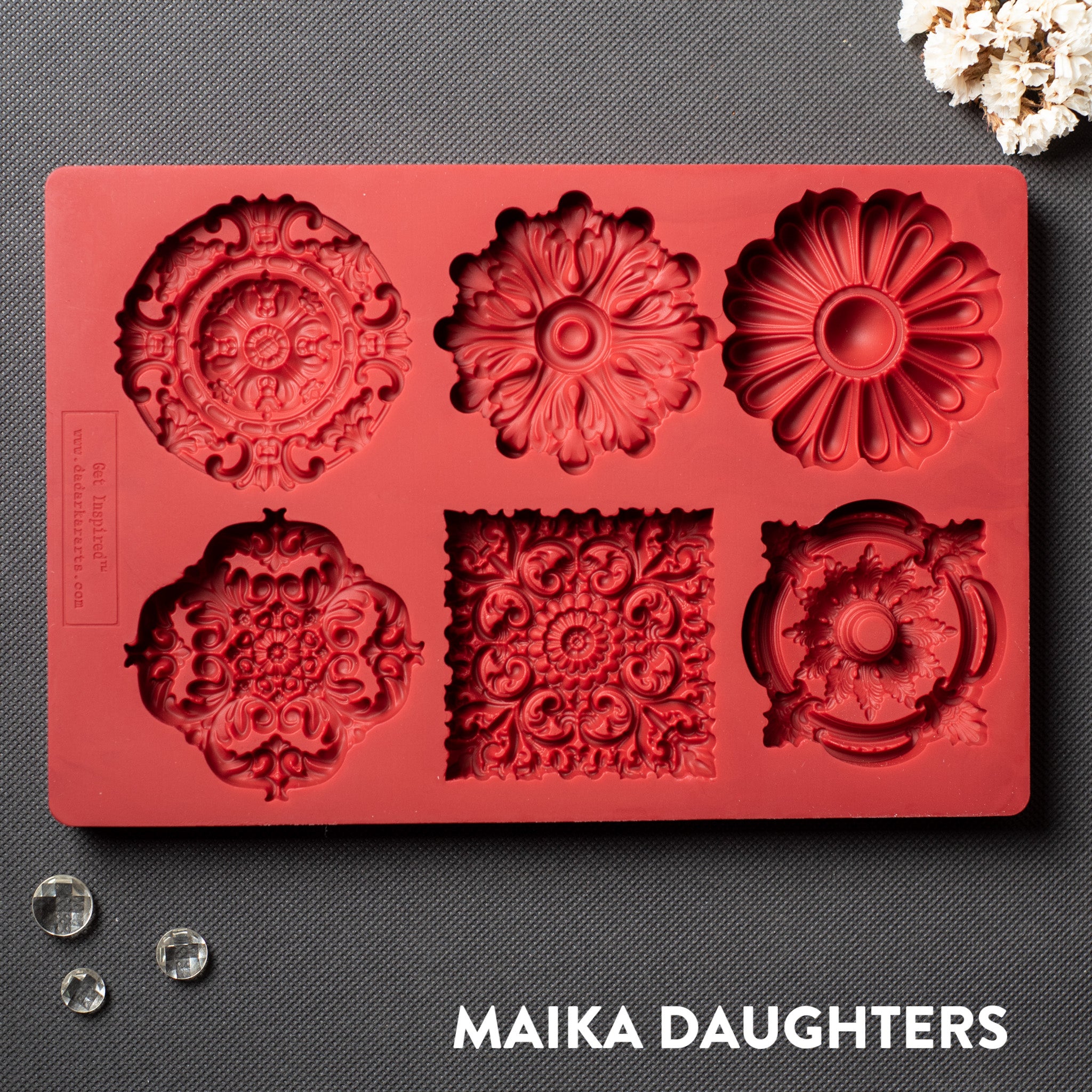 A red silicone mold of 5 round and 1 square ornate medallions is against a dark grey background.