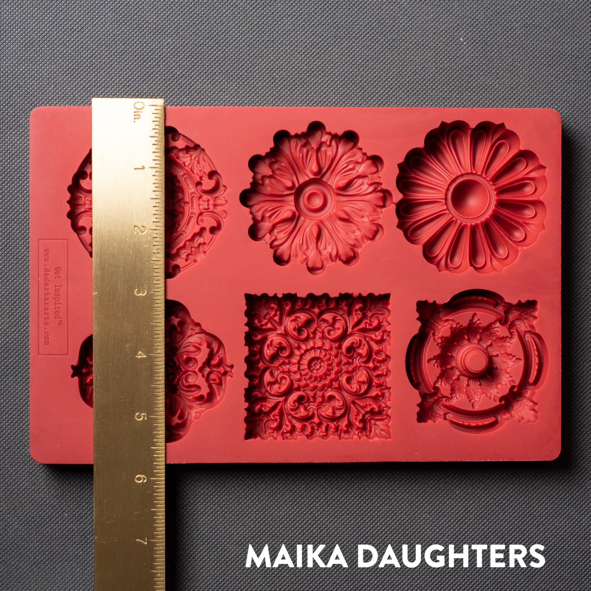 A red silicone mold featuring 6 ornate medallions is against a dark grey background. A gold ruler reading 5.75 inches height sits on the mold.