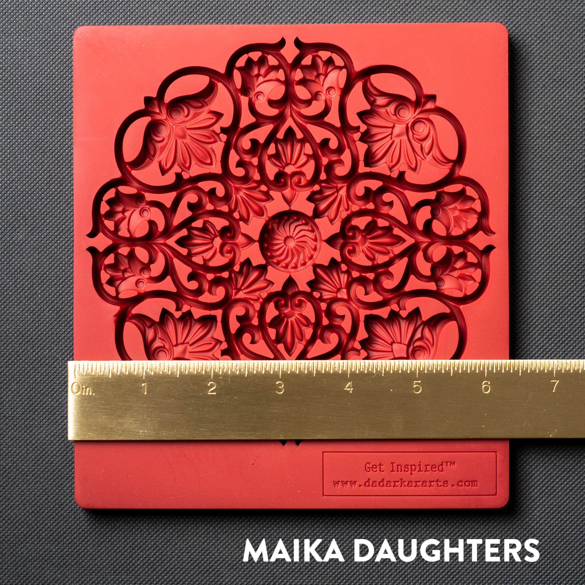 A red silicone mold of a large mandala with lotus flowers in it is against a dark grey background. A gold ruler reading 6.5" width is on the mold.