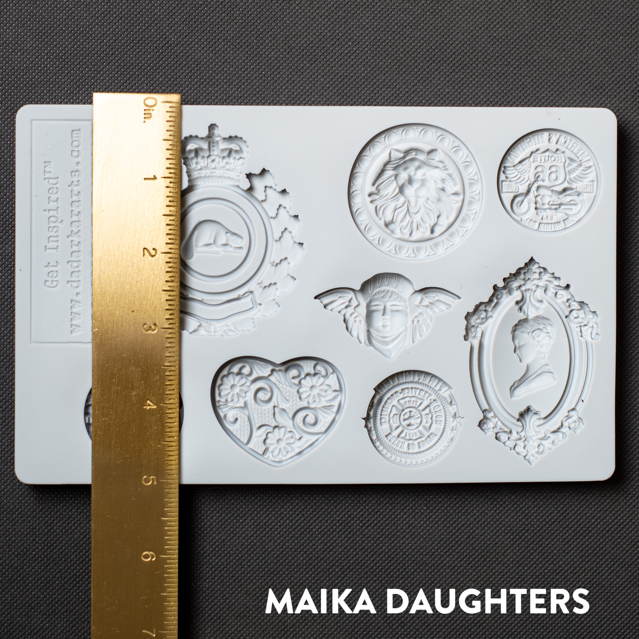 A light grey silicone mold of 8 ornate regal medallions is against a dark grey background. A gold ruler reading 5 inches height sits on the mold.