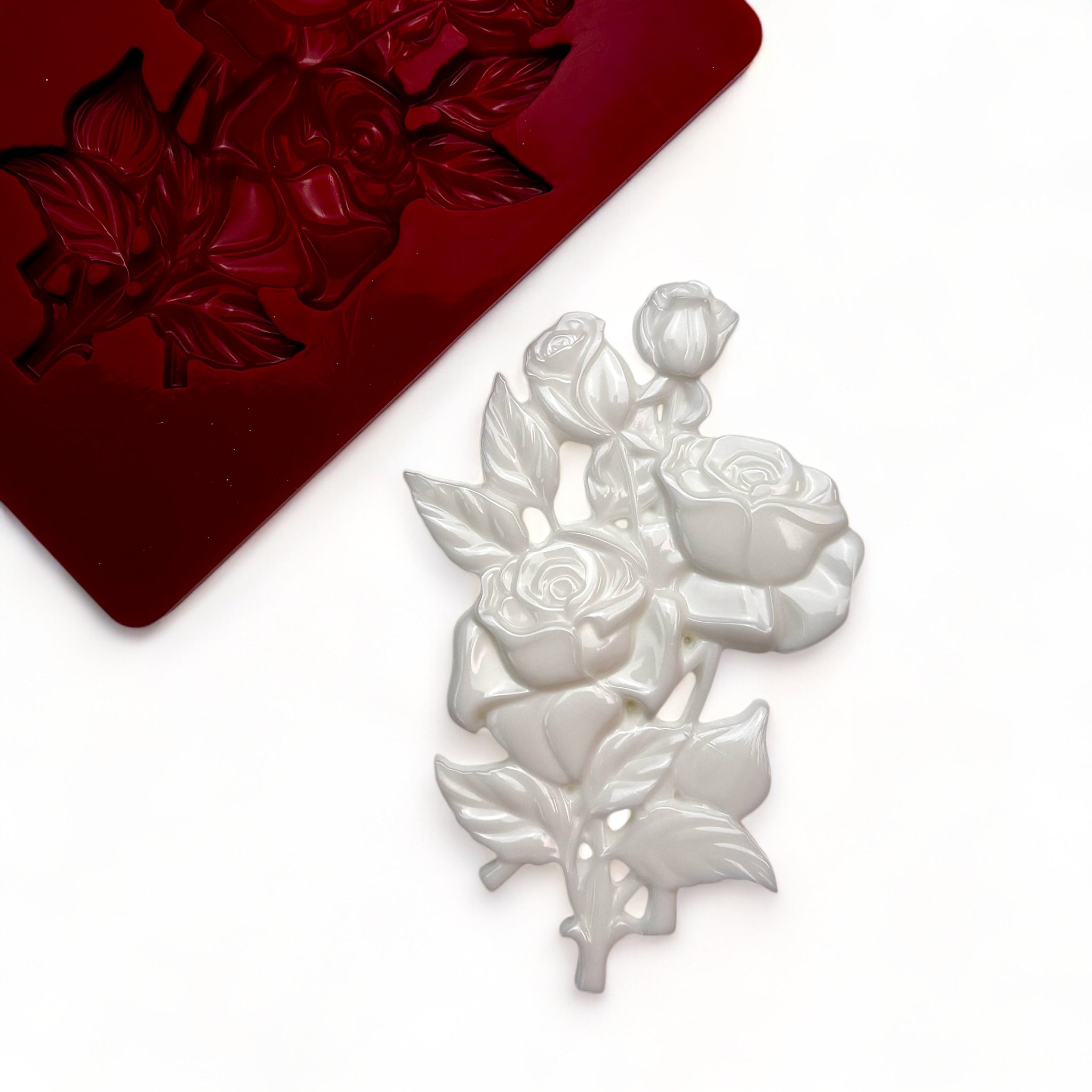 A red silicone mold and white resin casting of a small bouquet of roses are against a white background.