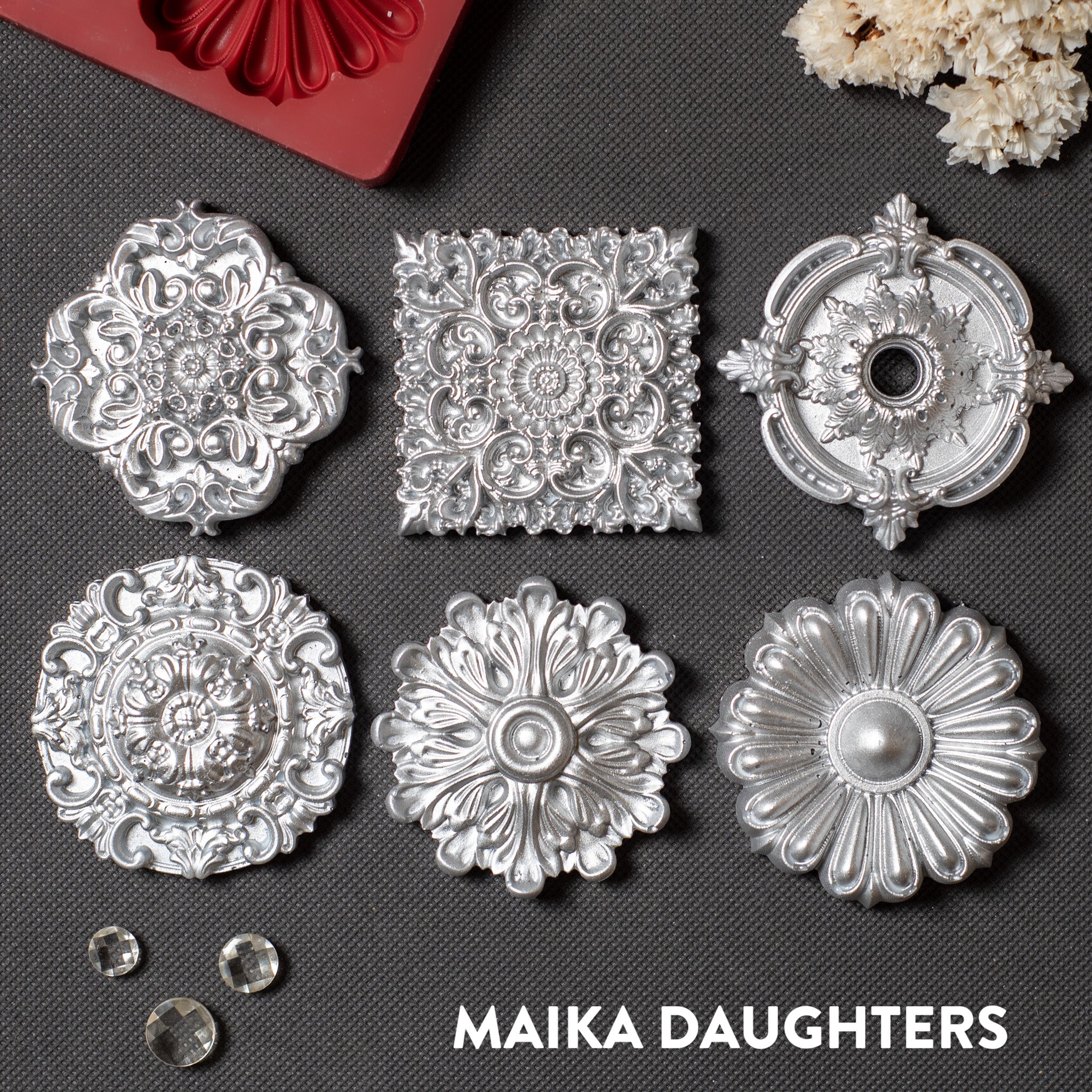 Silver colored castings of 5 round and 1 square ornate medallions are against a dark grey background.