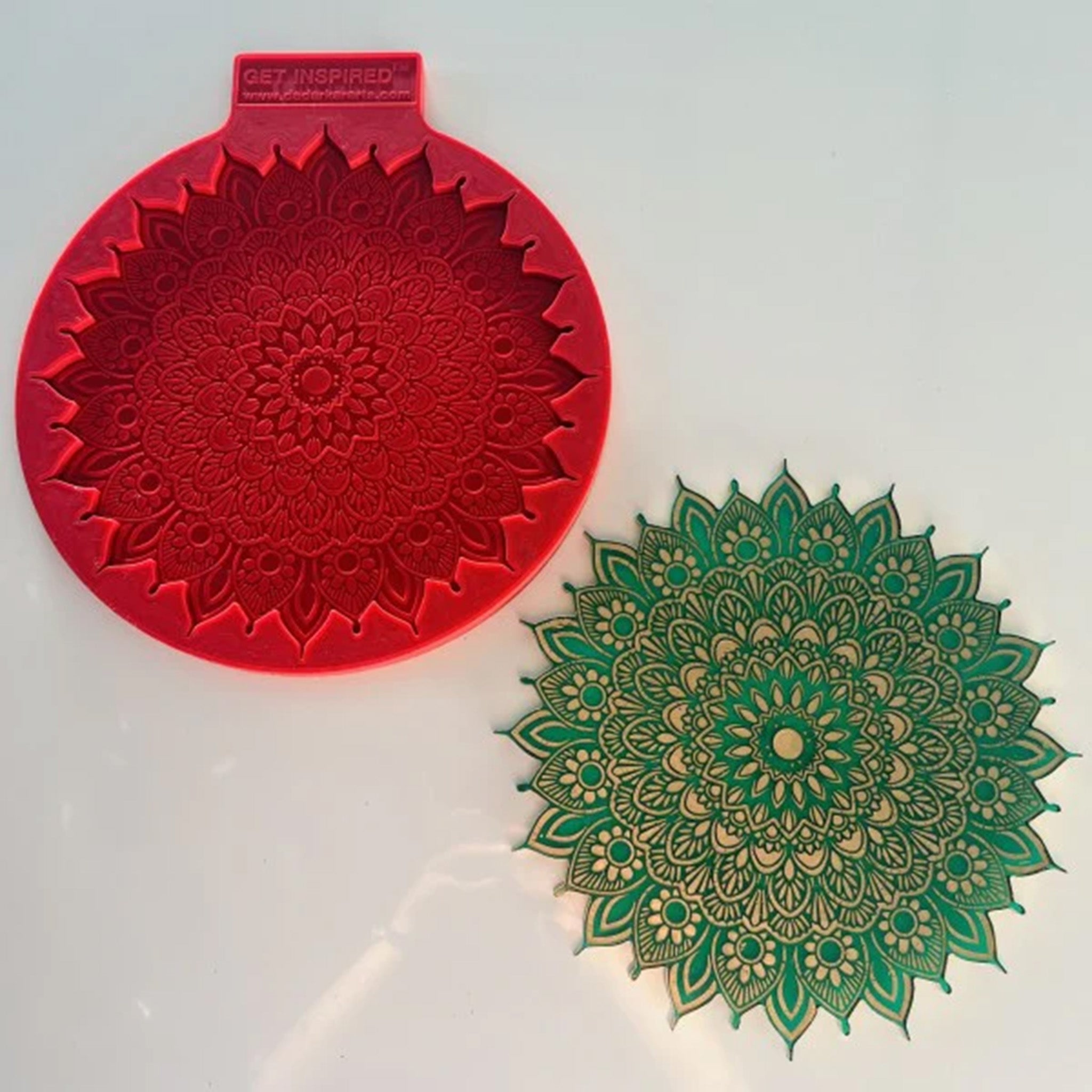 A red silicone mold and green and gold painted casting of a large mandala with paisleys are against a white background.