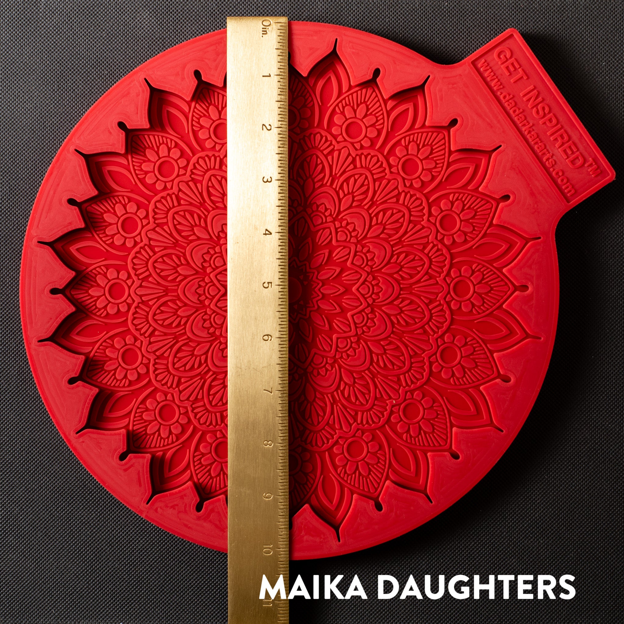 A red silicone mold featuring a large mandala with paisleys is against a dark grey background. A gold ruler reading 11 inches width sits on the mold.