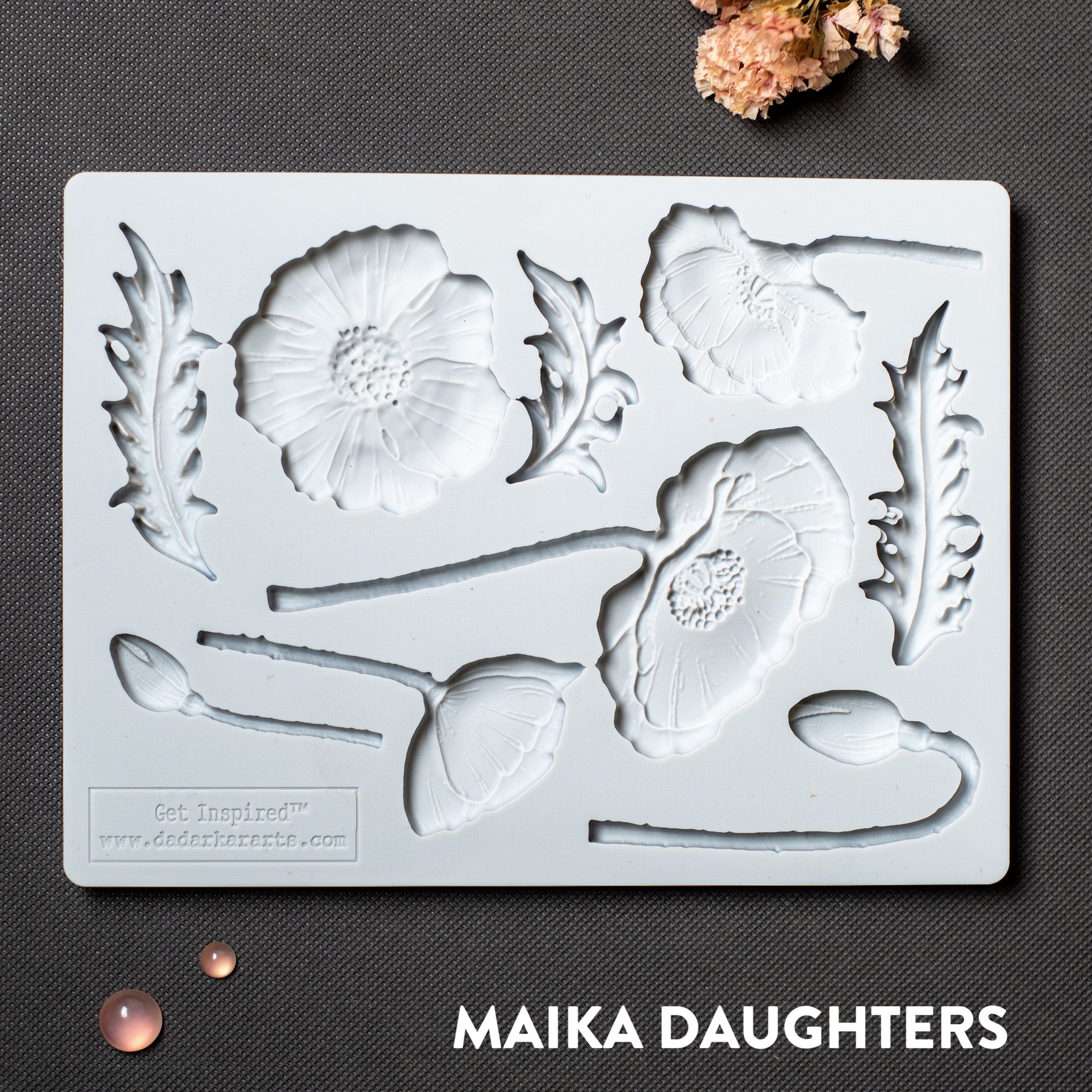 A light grey silicone mold featuring flower blooms, buds, and leaves is against a dark grey background.