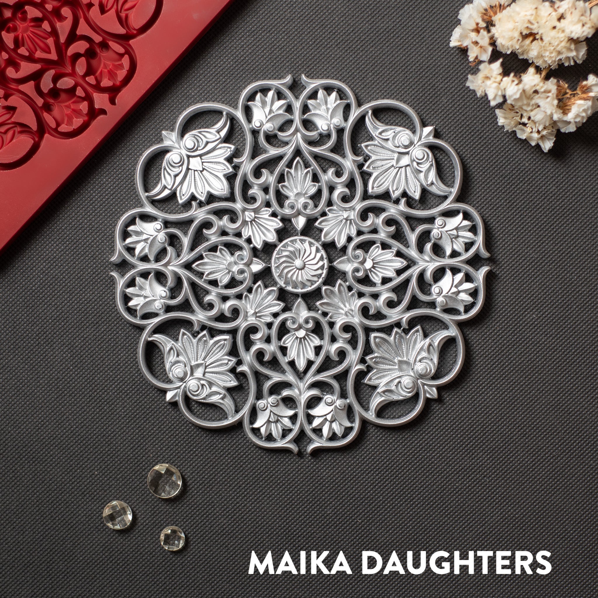 A silver colored casting of a large mandala with lotus flowers in it is against a dark grey background.