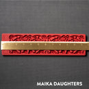 A red silicone mold of an ornate border is against a dark grey background. A gold ruler reding 11.5 inches length sits on the mold.