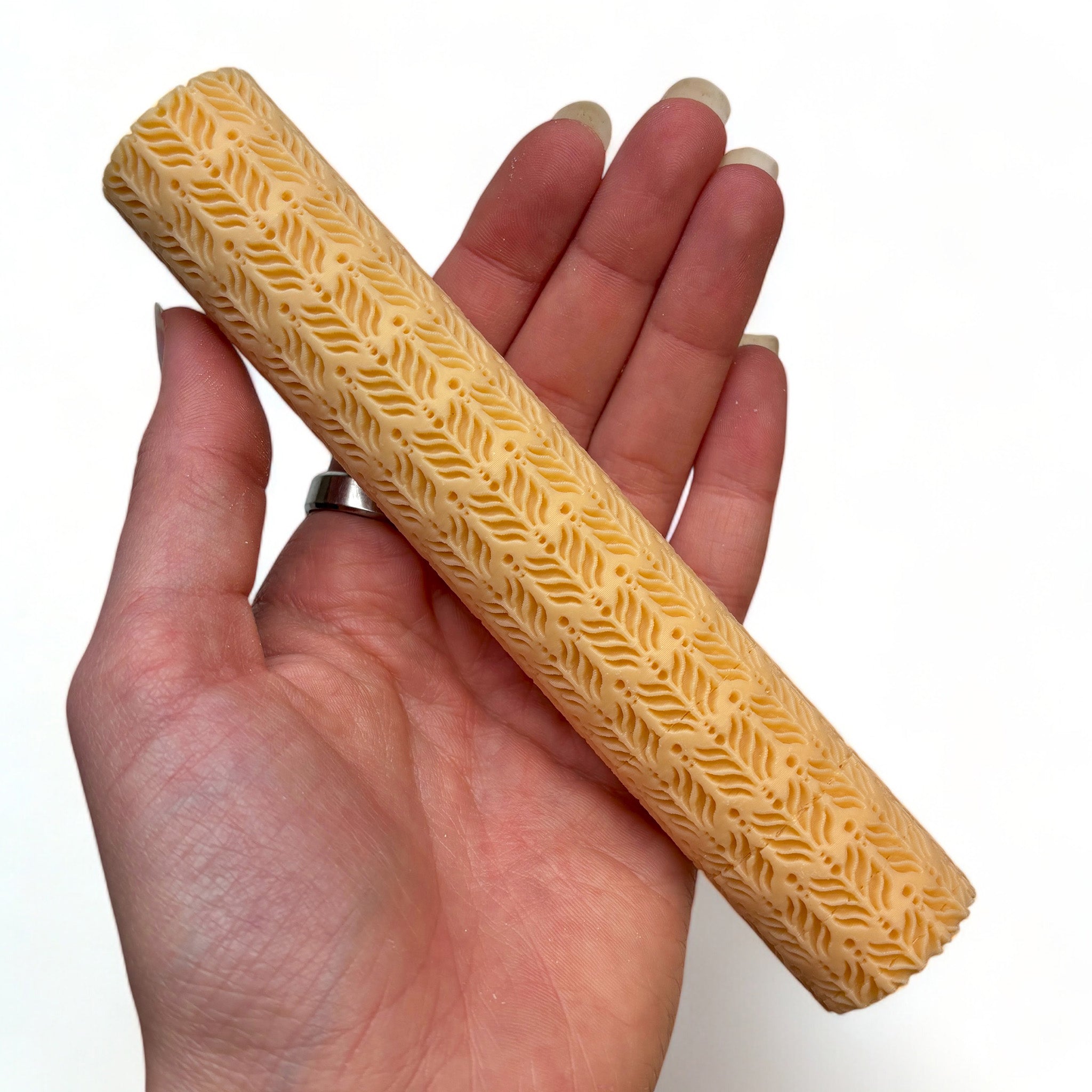 A hand is shown holding Dadakar Art's Cacia Leaves Pattern Texture Roller against a white background.
