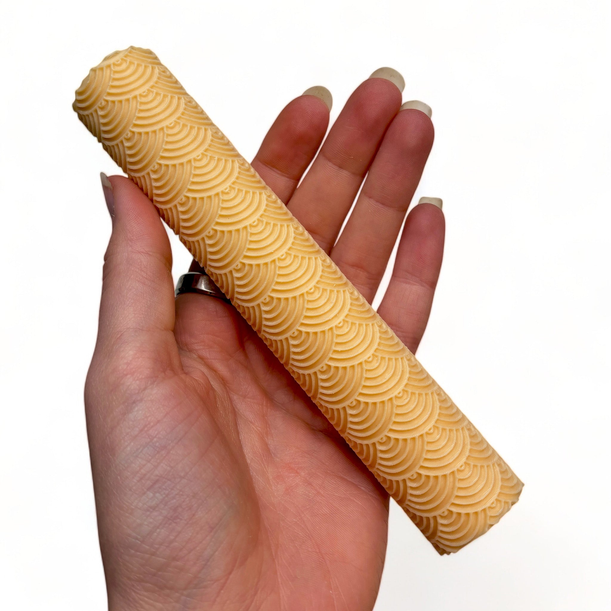 A hand is shown holding Dadakar Art's Scallop Curve Texture Roller against a white background.
