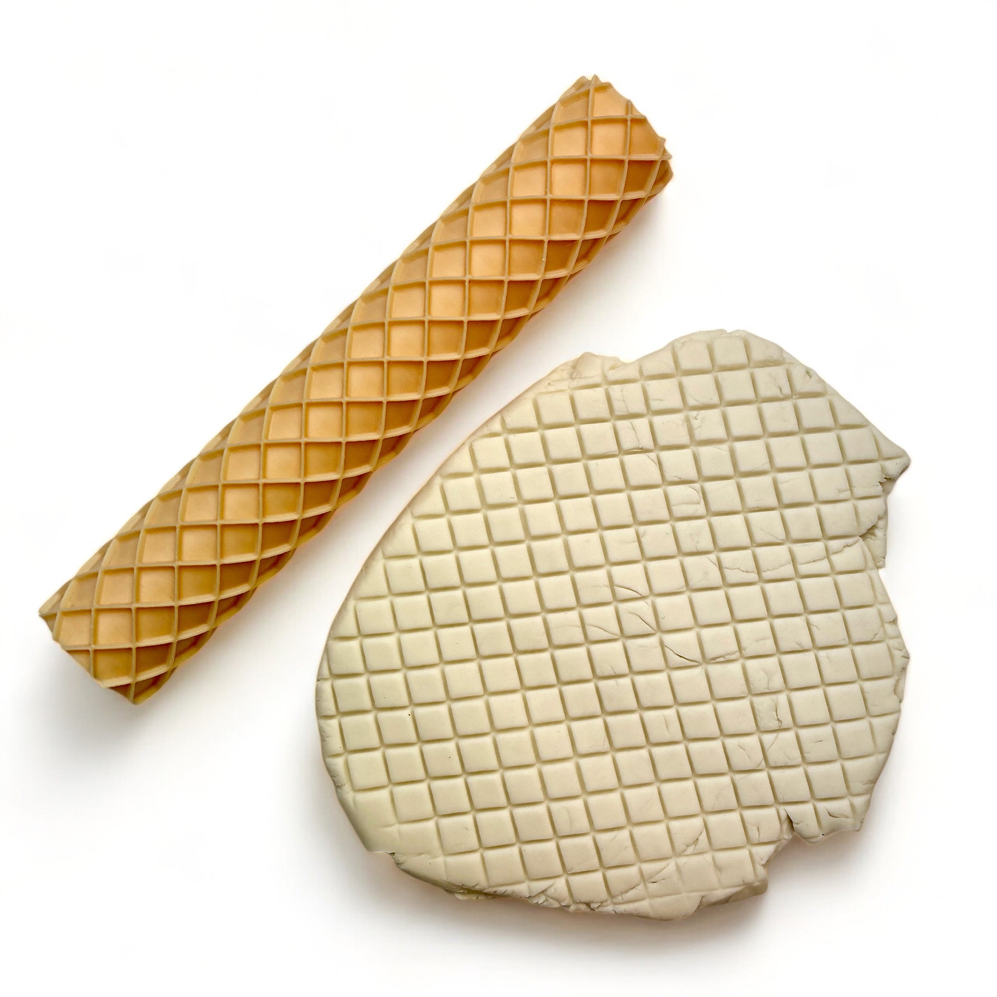 A seamless texture roller and flattened chunk of clay featuring a waffle pattern are against a white background.