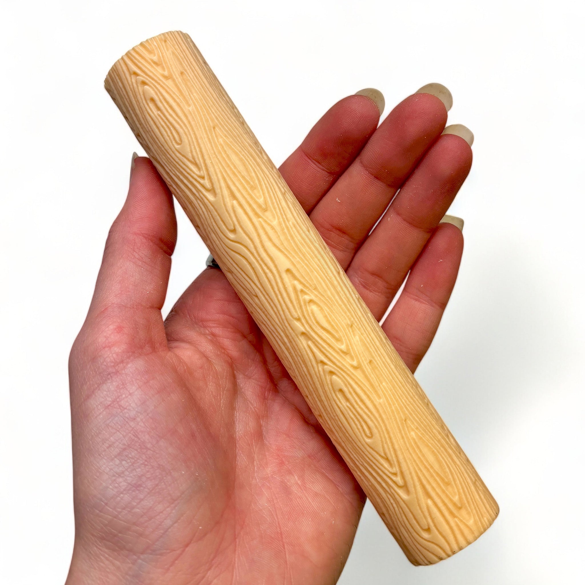 A hand is shown holding Dadakar Art's Wood Love Texture Roller against a white background.
