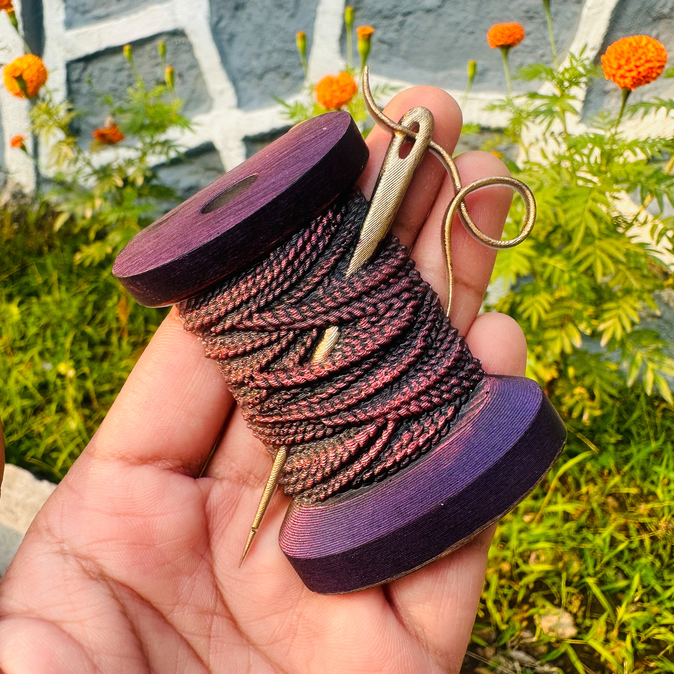 A hand is shown holding the spool of thread with a needle in it casting created from Get Inspired by Dadarkar Art's Feminine Treasures silicone mold.