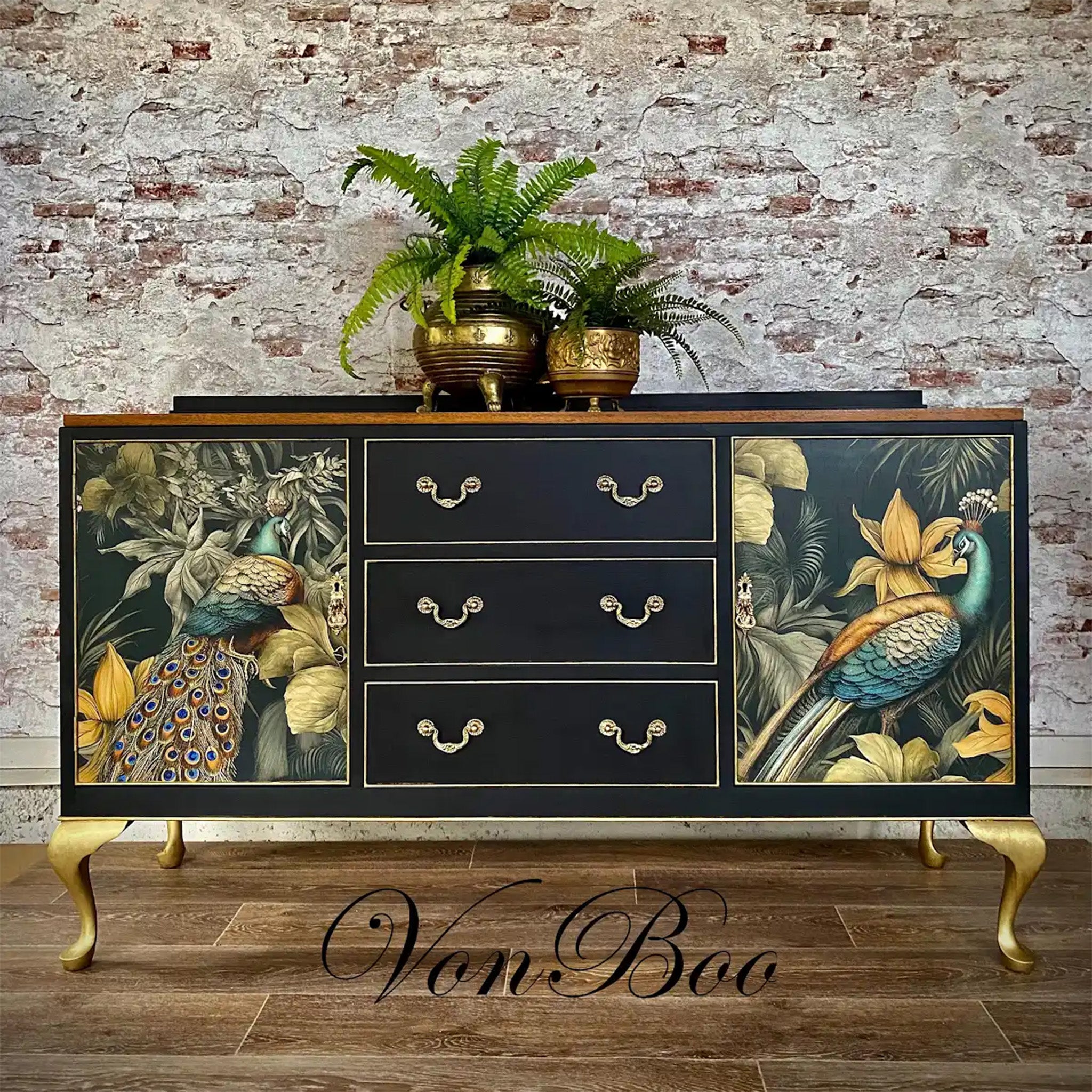 A vintage console table refurbished by Von Boo is painted black with gold legs and features Mint by Michelle's A Peacock Pair rice paper on its 2 doors.