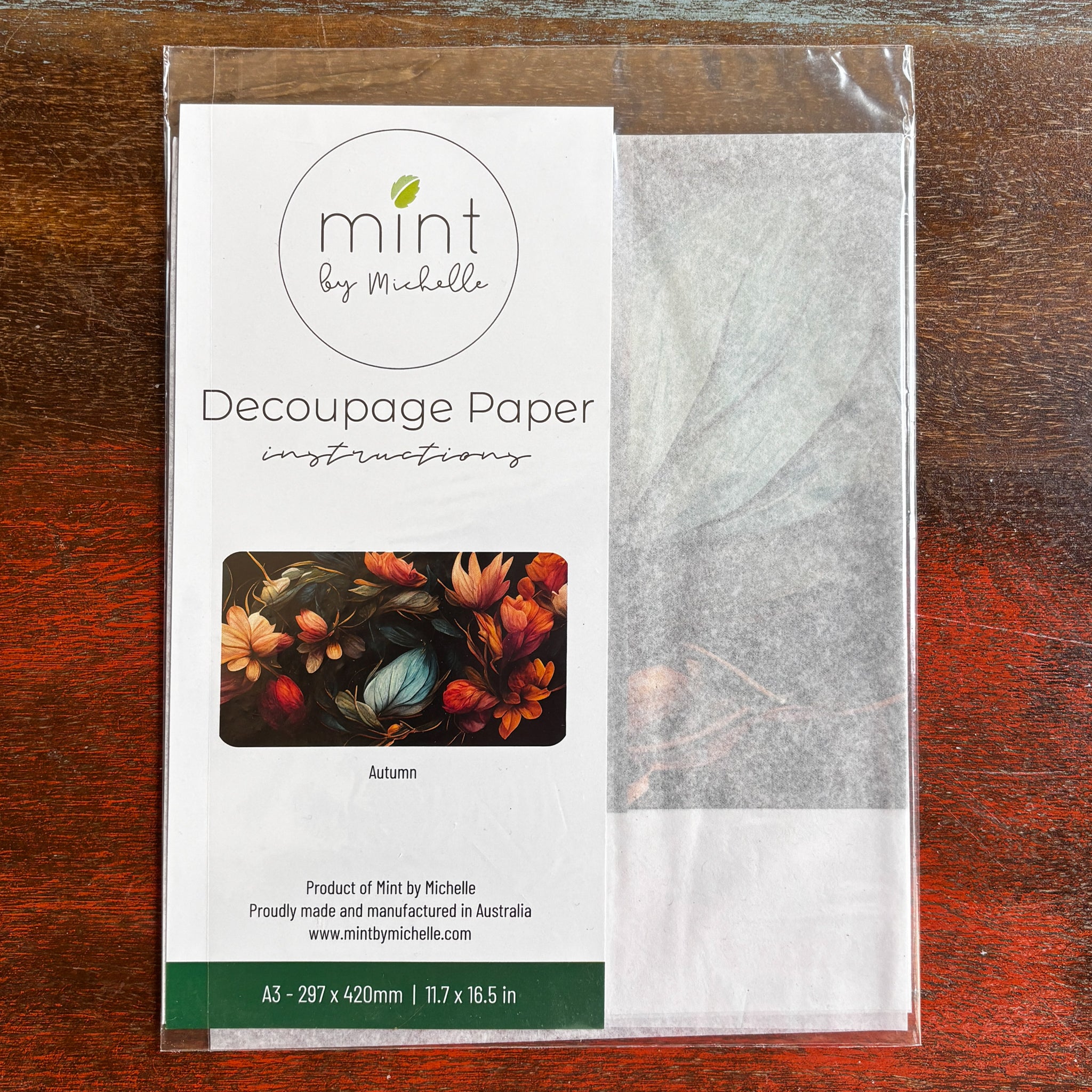 A package of Mint by Michelle's Autumn A3 decoupage paper is against a dark wood background.