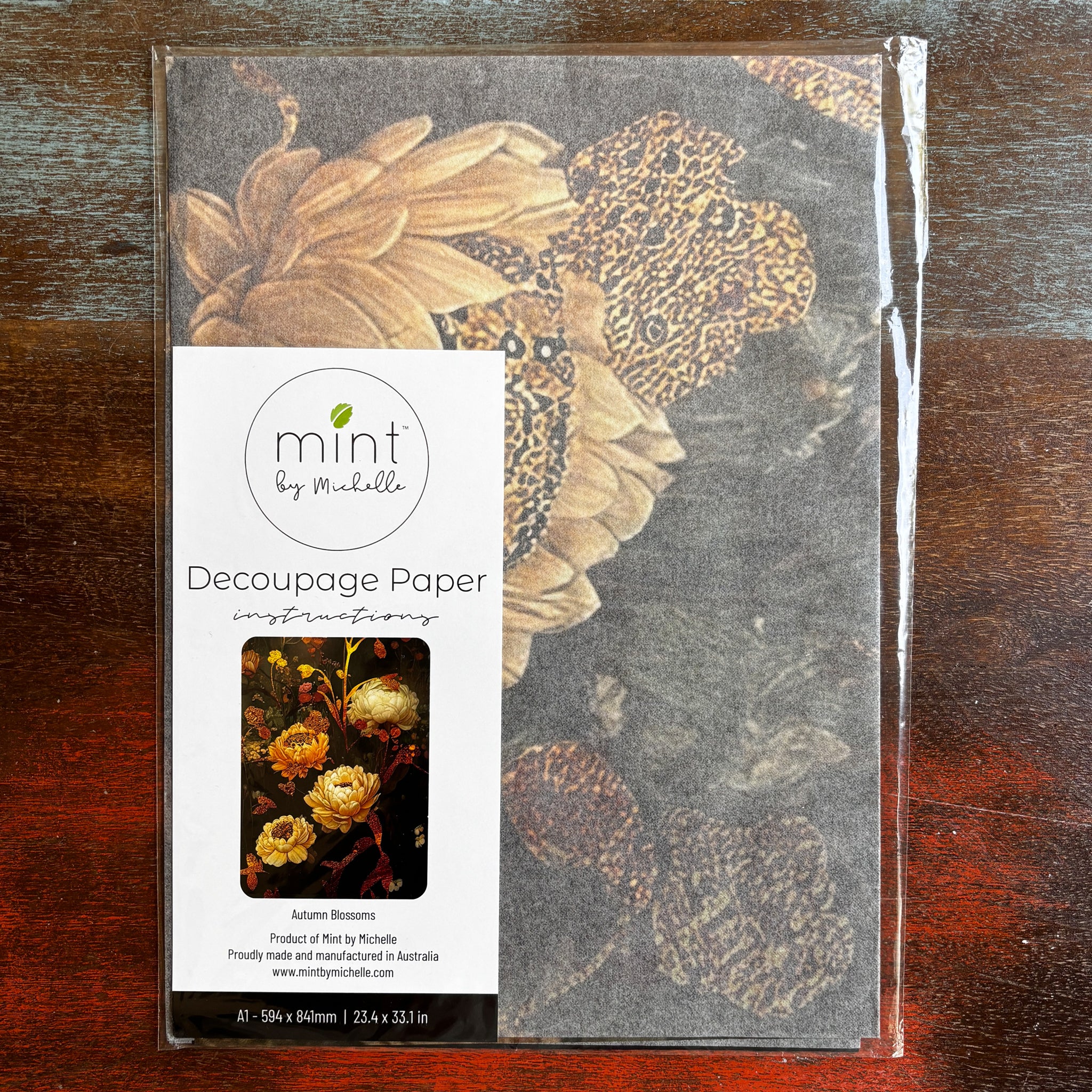 A package of Mint by Michelle's Autumn Blossoms A1 decoupage paper is against a dark wood background.