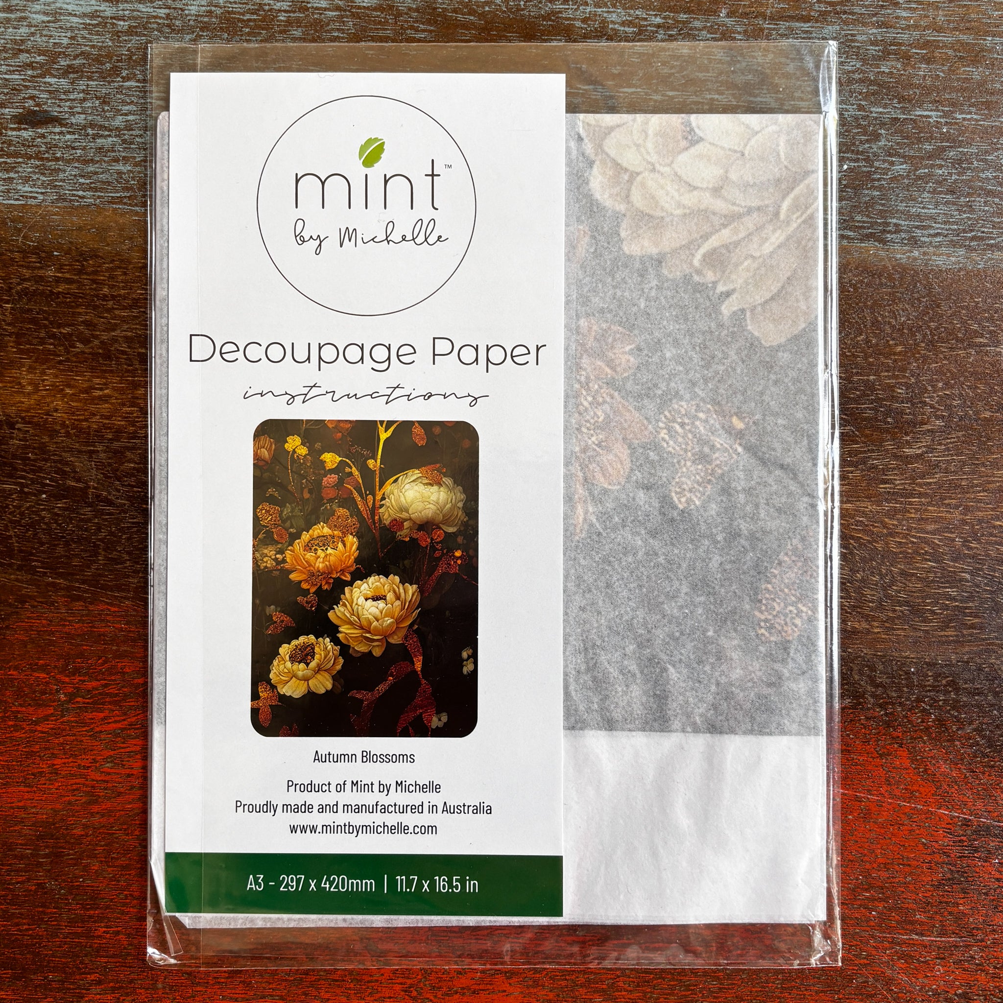 A package of Mint by Michelle's Autumn Blossoms A3 decoupage paper is against a dark wood background.