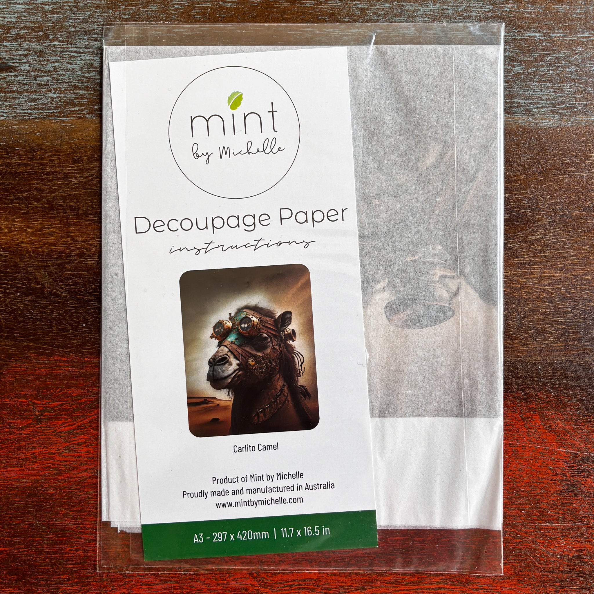 A package of Mint by Michelle's Carlito Camel A3 decoupage paper is against a dark wood background.