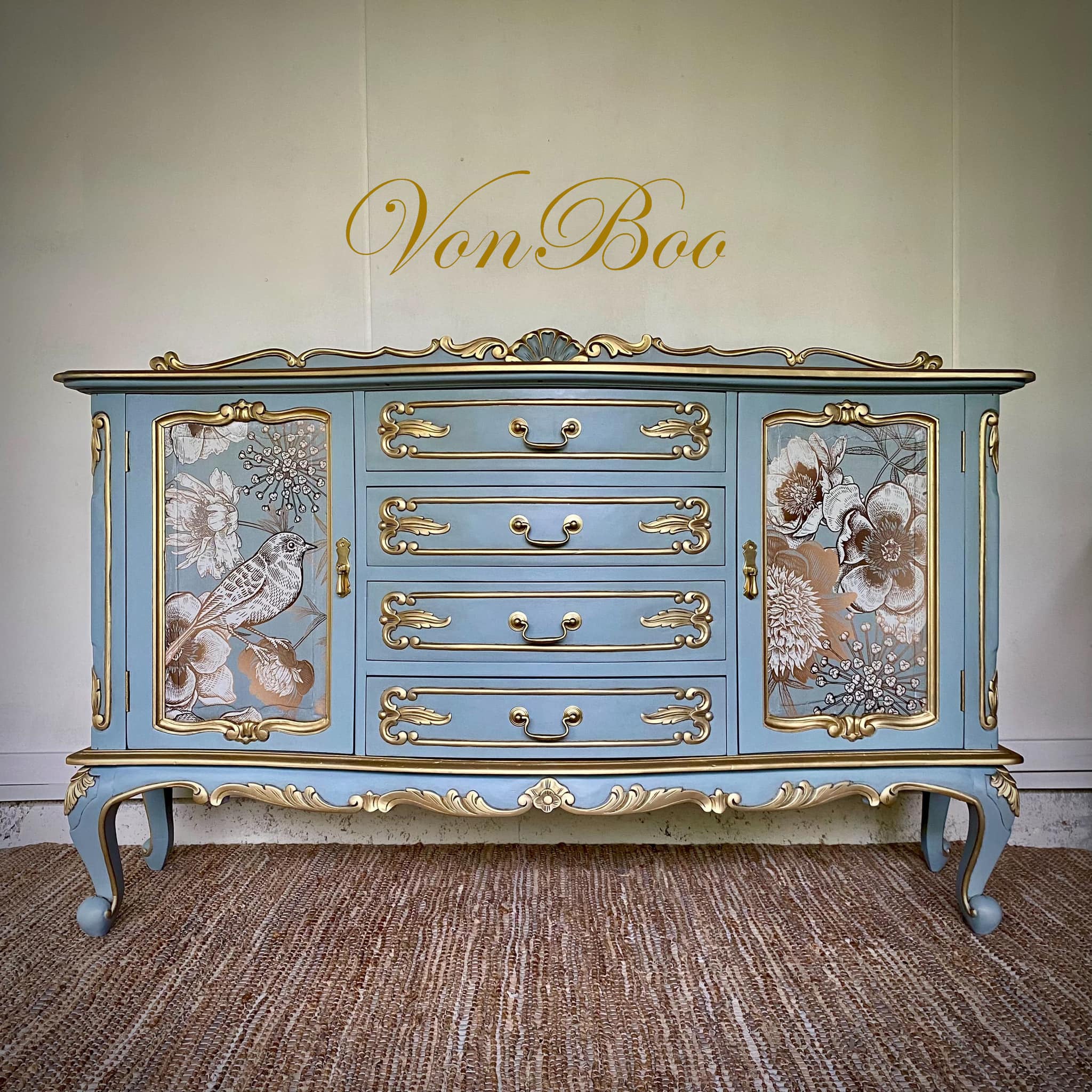 A vintage French Provincial large buffet cabinet refurbished by Von Boo is painted light blue with gold accents and features Mint by Michelle's Foil Birds decoupage paper on its 2 doors. 