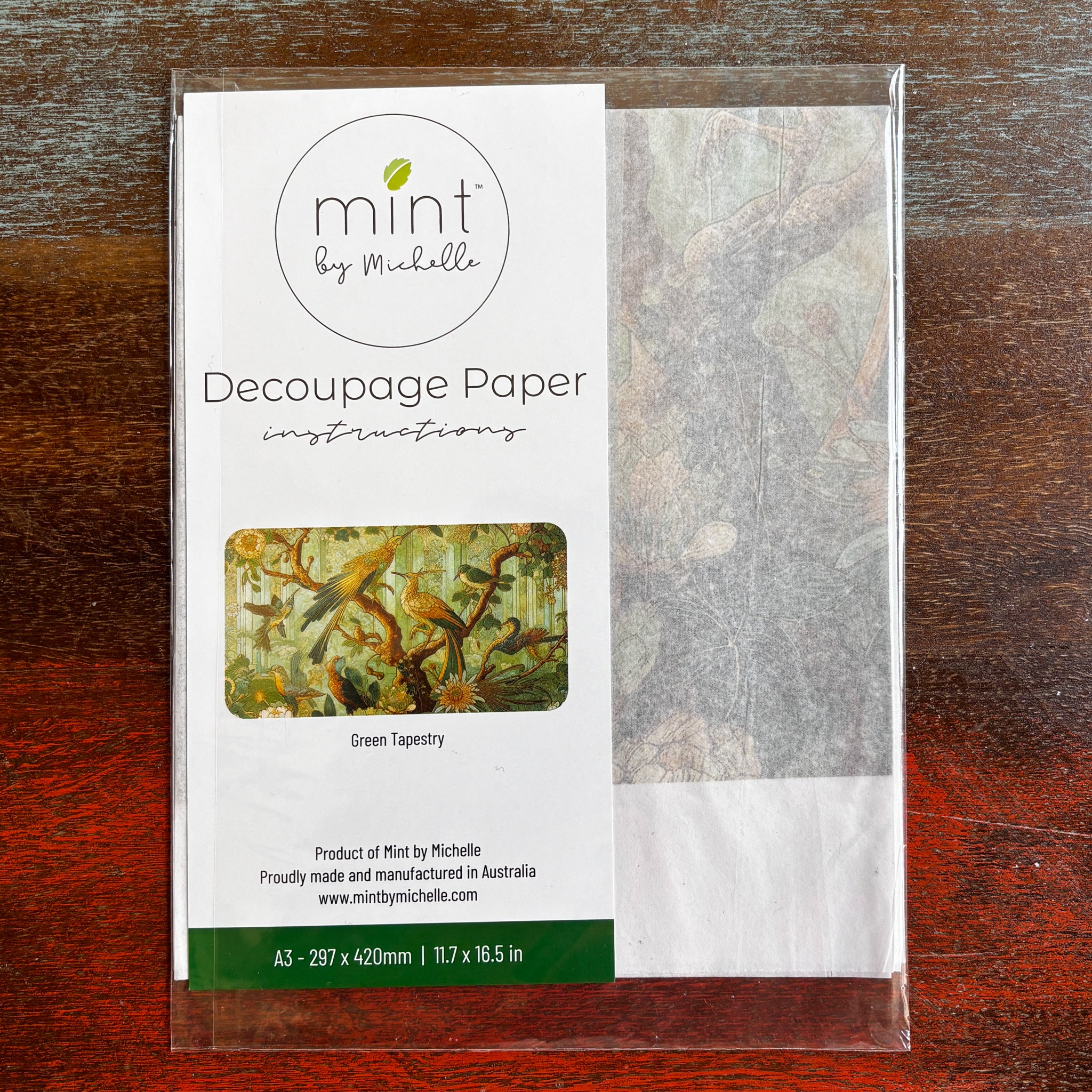 A package of Mint by Michelle's Green Tapestry A3 decoupage paper is against a dark wood background.