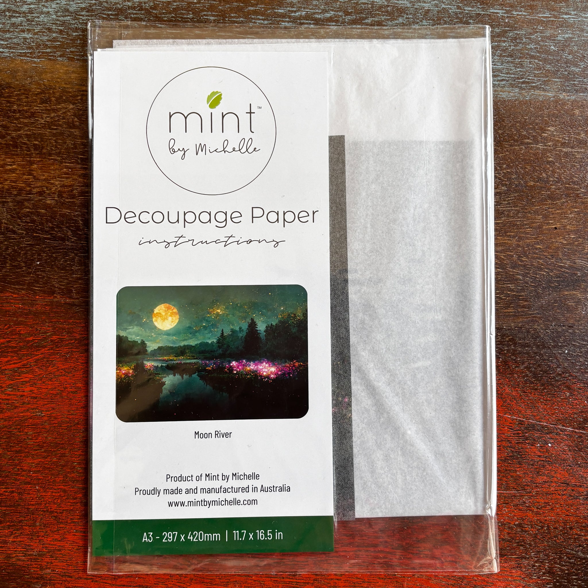 A package of Mint by Michelle's Moon River A3 decoupage paper is against a dark wood background.