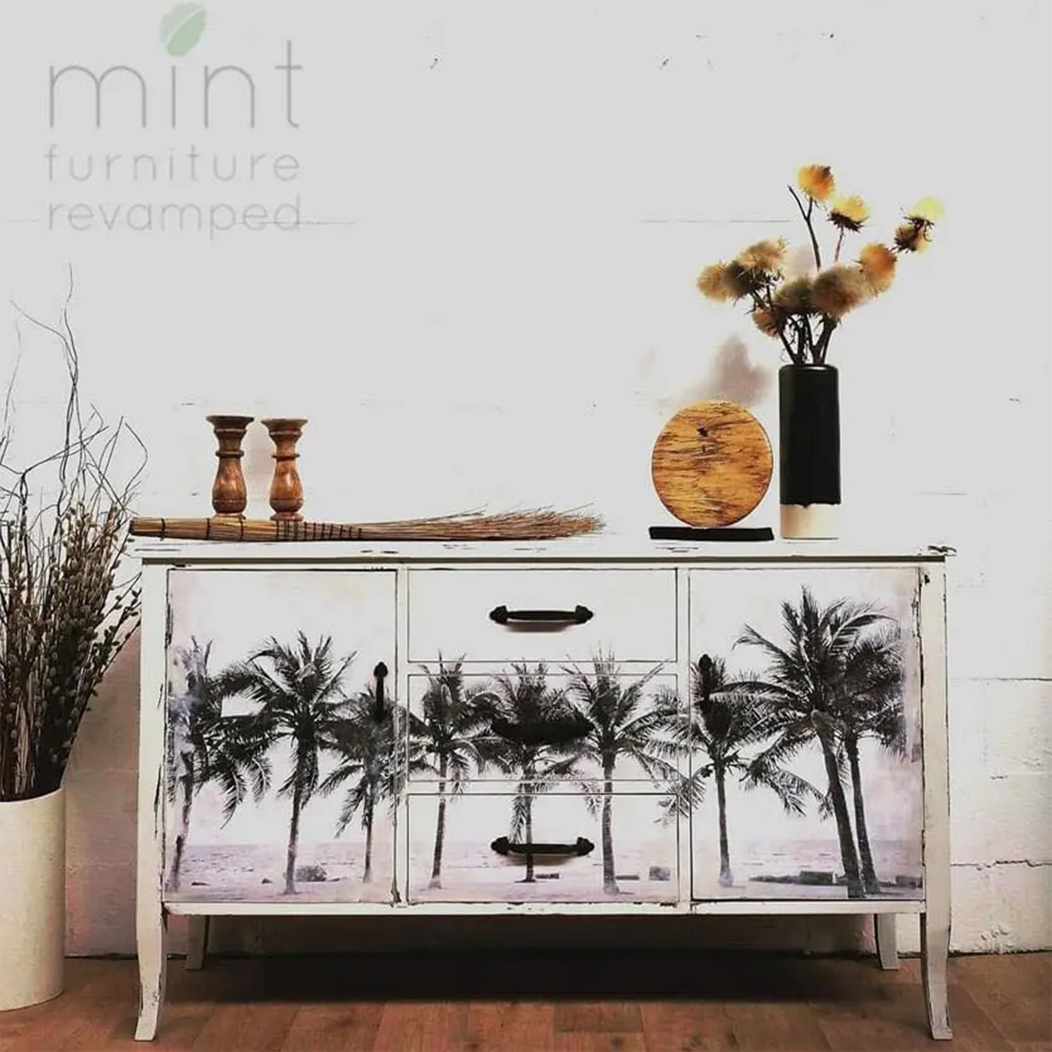 A console table refurbished by Mint Furniture Revamped is painted white and features Mint by Michelle's Palm Trees decoupage paper on its doors and drawers.