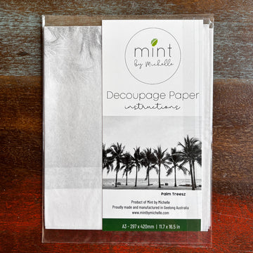 A package of Mint by Michelle's Palm Trees A3 decoupage paper is against a dark wood background.