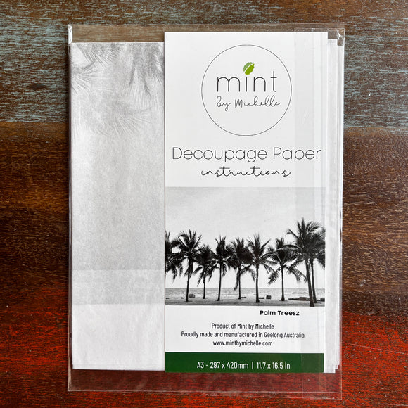 A package of Mint by Michelle's Palm Trees A3 decoupage paper is against a dark wood background.