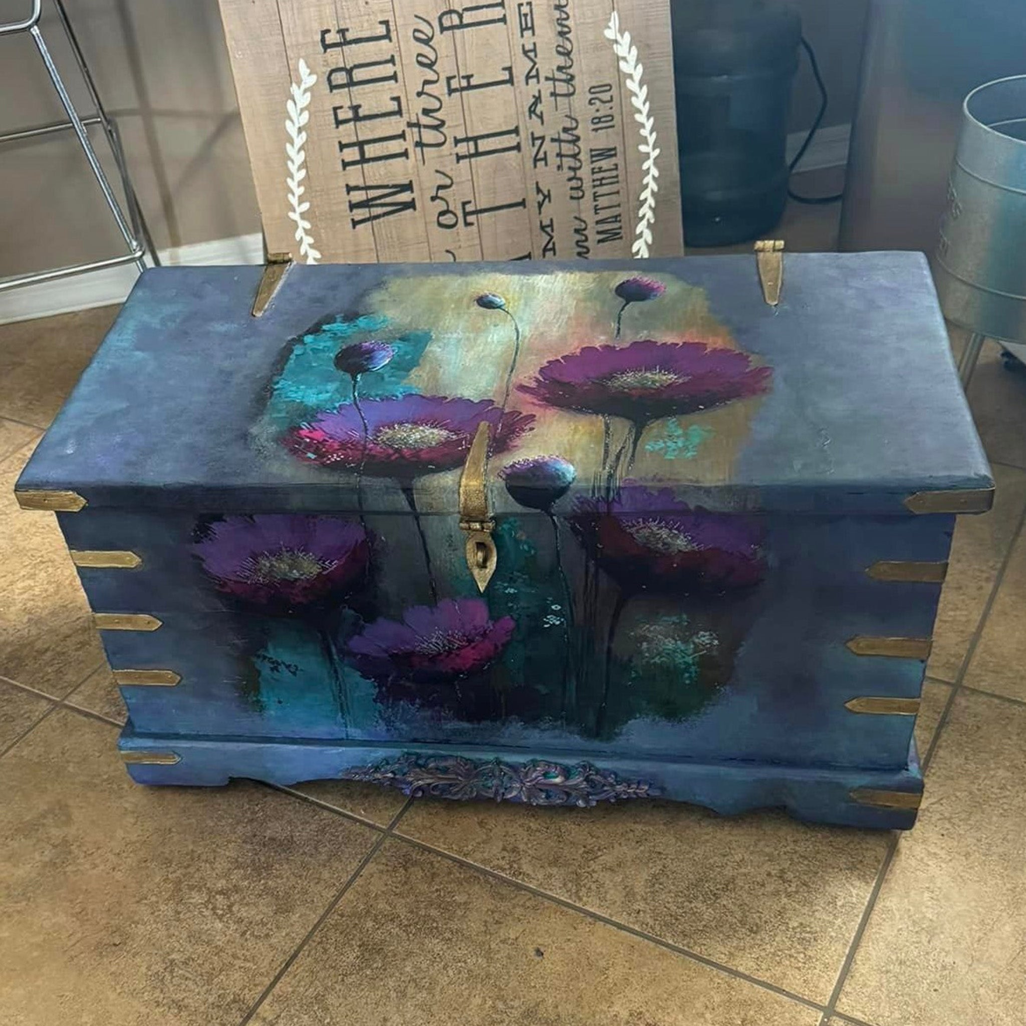 A vintage storage chest is painted blue with gold hardware and features Whimsykel's Purple Poppies tissue paper on it.