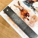 A close-up of Decoupage Queen's Four Abundance Scenes A4 rice paper shows a silver ruler over one of the designs showing a measurement of 5.75 inches high.