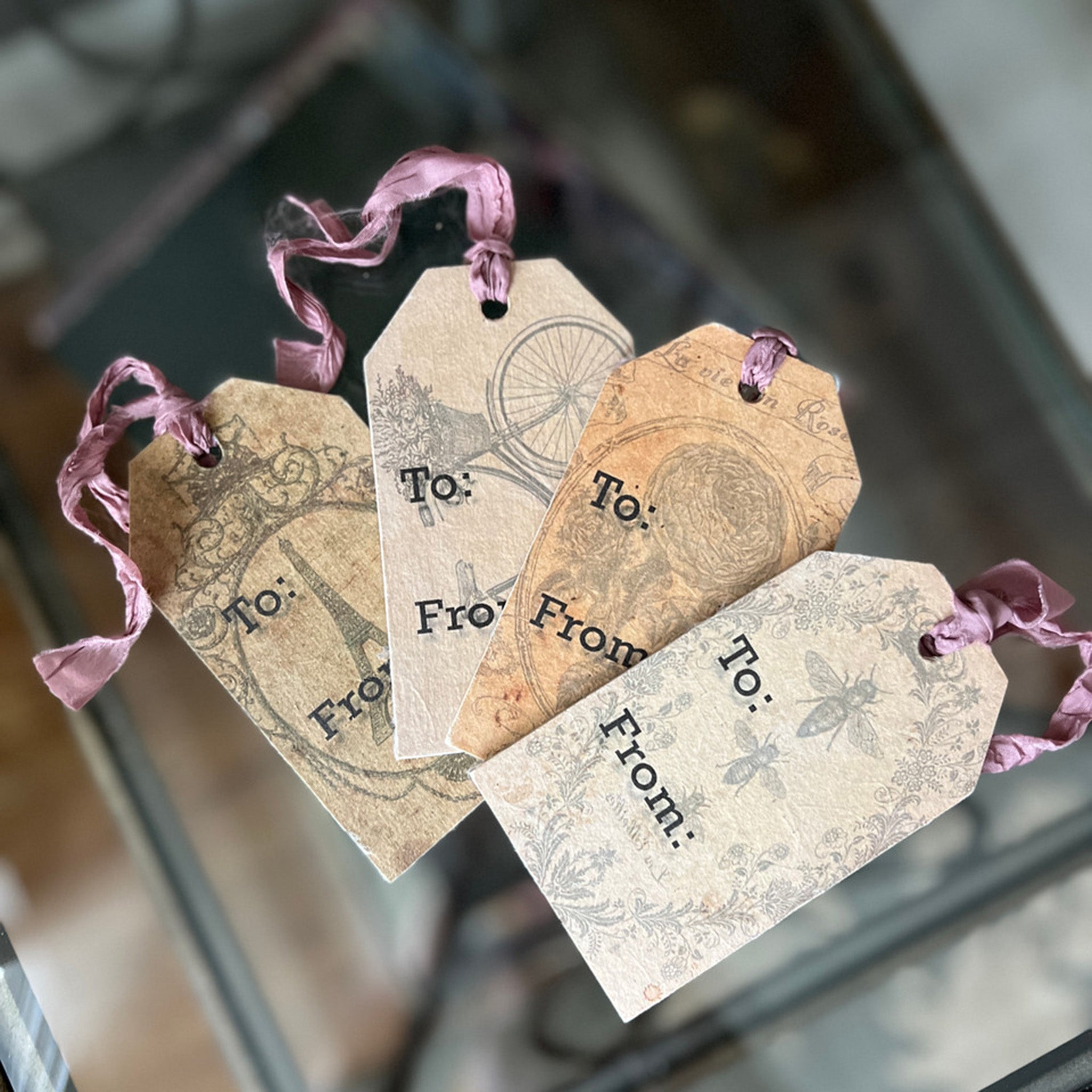 Four wood tags created using Decoupage Queen's beginner's decoupage kit are on a glass table.