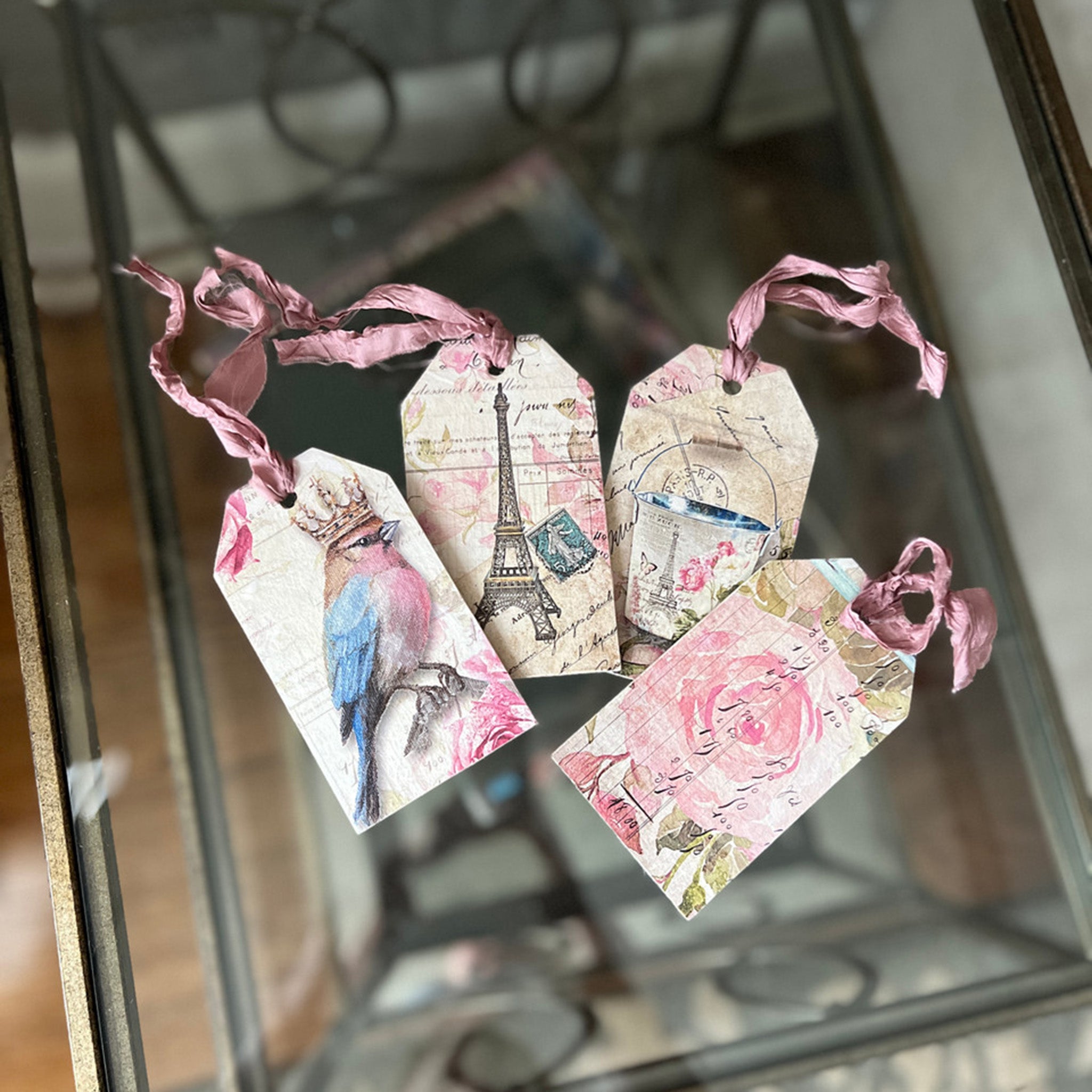 Four wood tags created using Decoupage Queen's beginner's decoupage kit are on a glass table.