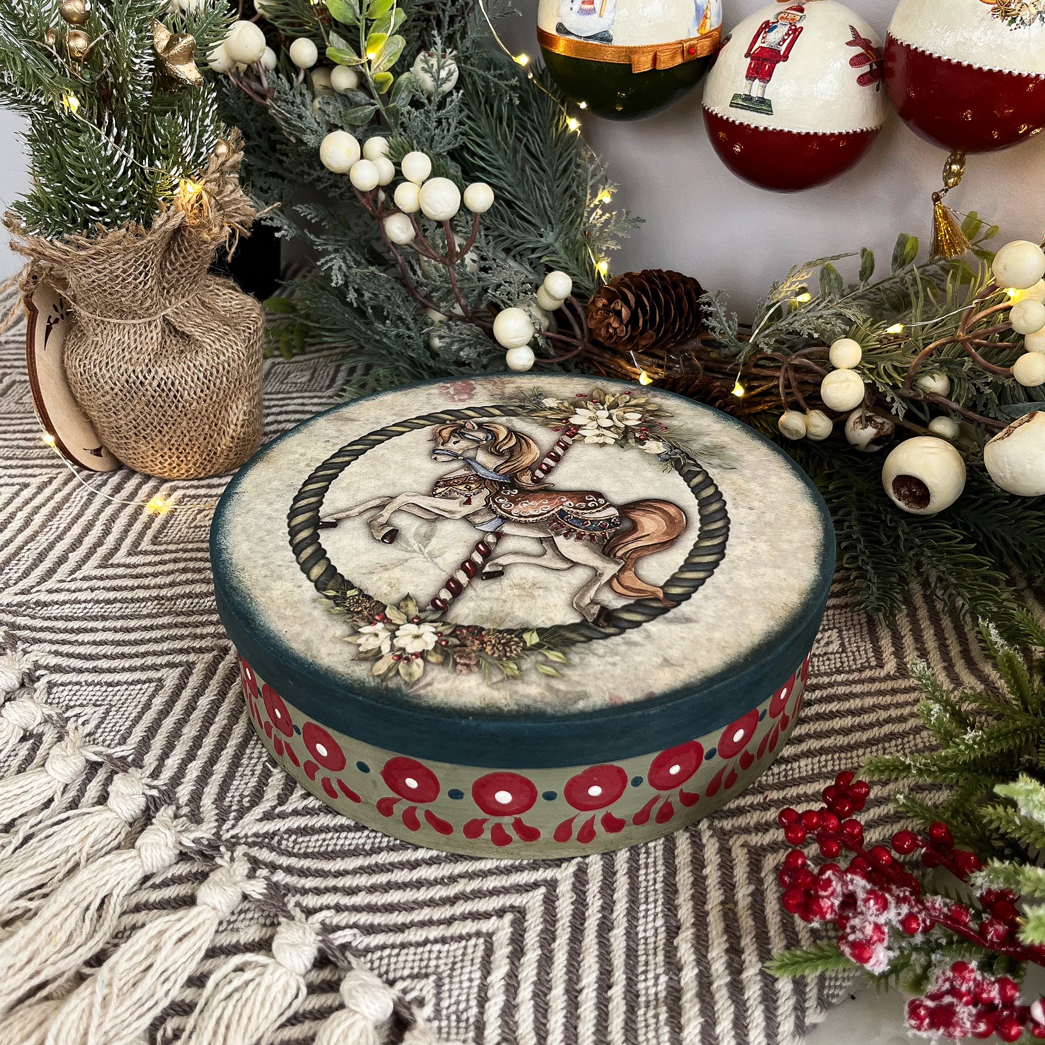 A cookie tin is painted in festive holiday colors and features Decoupage Queen's Carousel 1 rice paper on the lid.