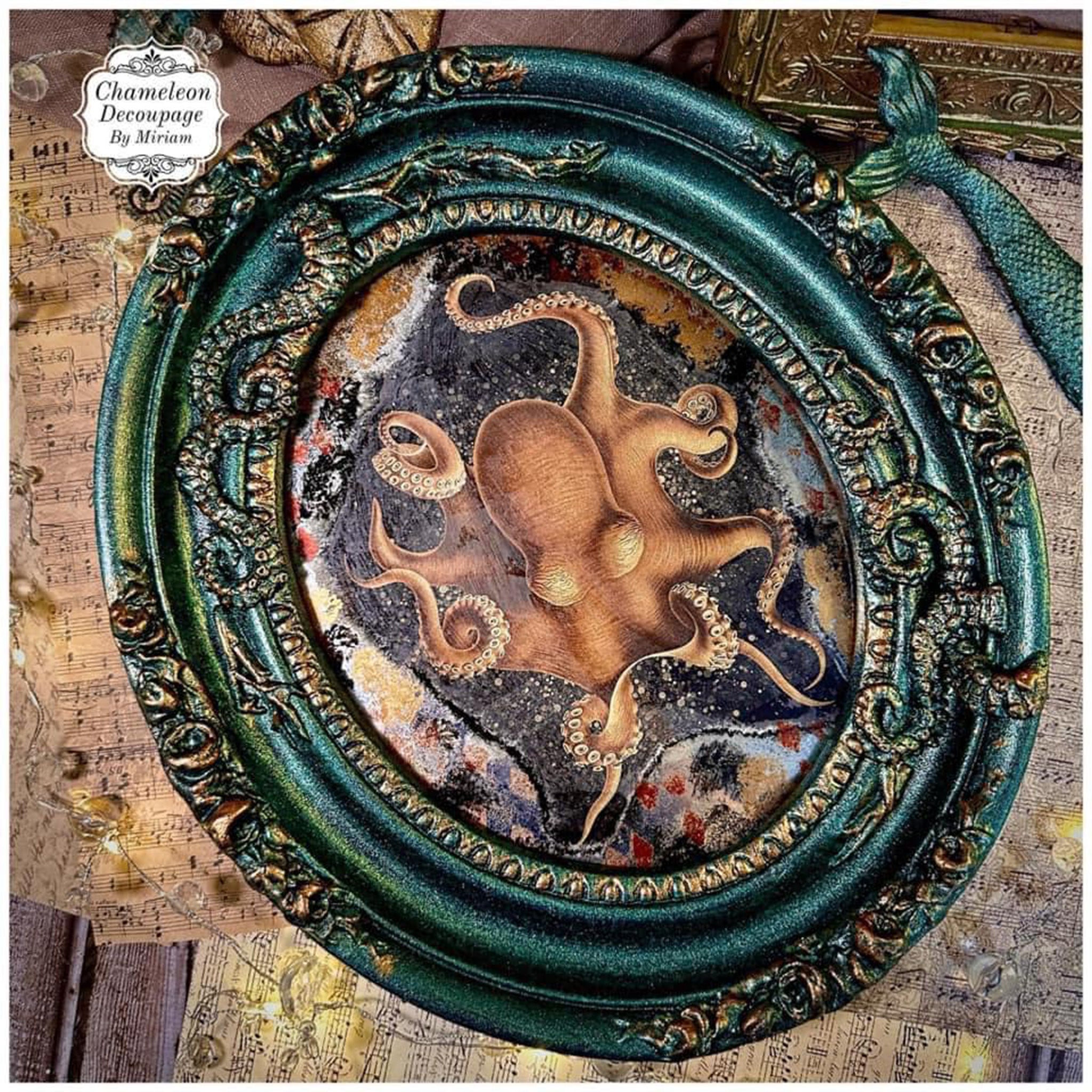 An ornate oval frame refurbished by Chameleon Decoupage by Miriam is painted in color shifting dark green and features Decoupage Queen's Mollusca rice paper on it.