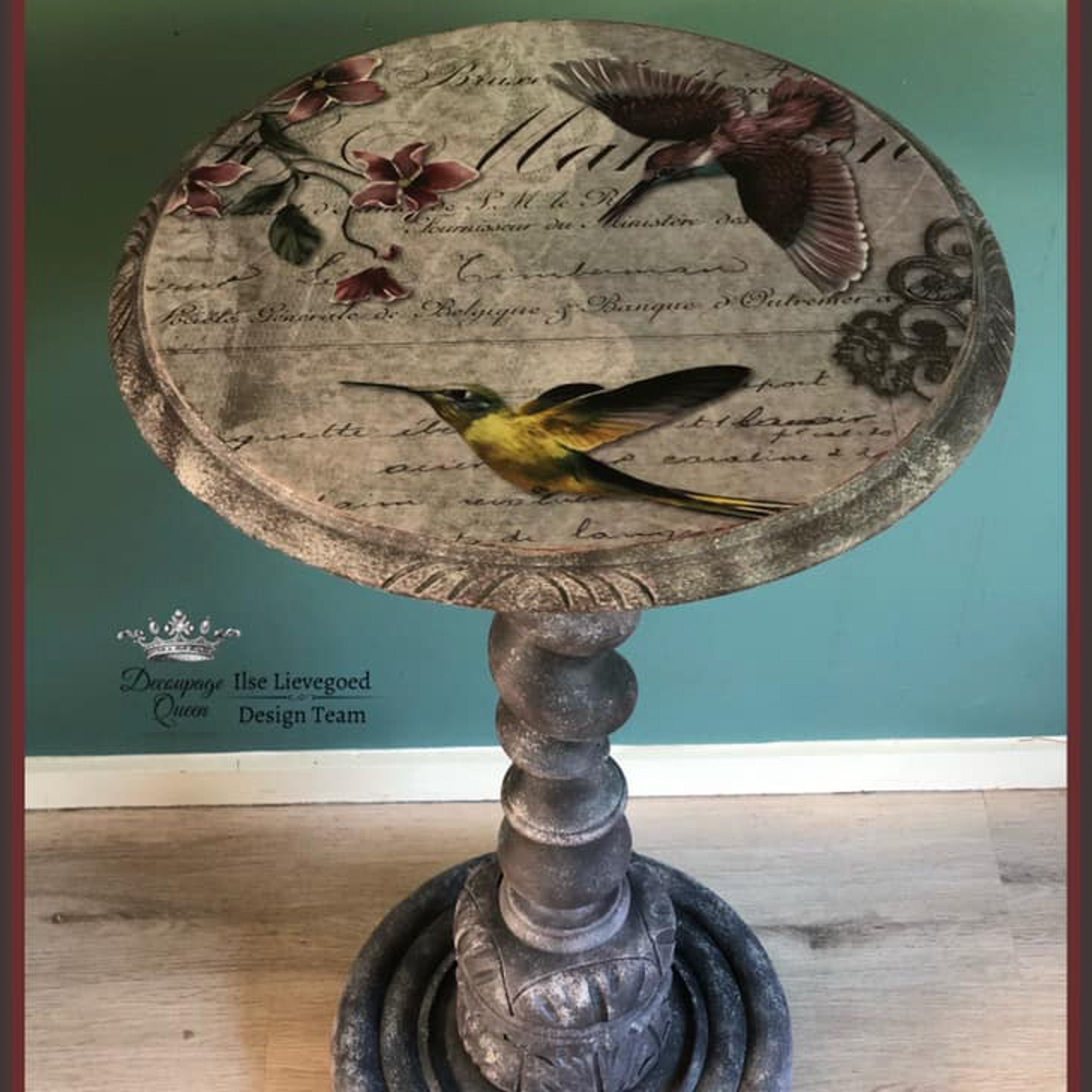 A small stone plant stand refurbished by Ilse Lievegoed Design Team features Decoupage Queen's Hummingbird Song rice decoupage paper on the top.