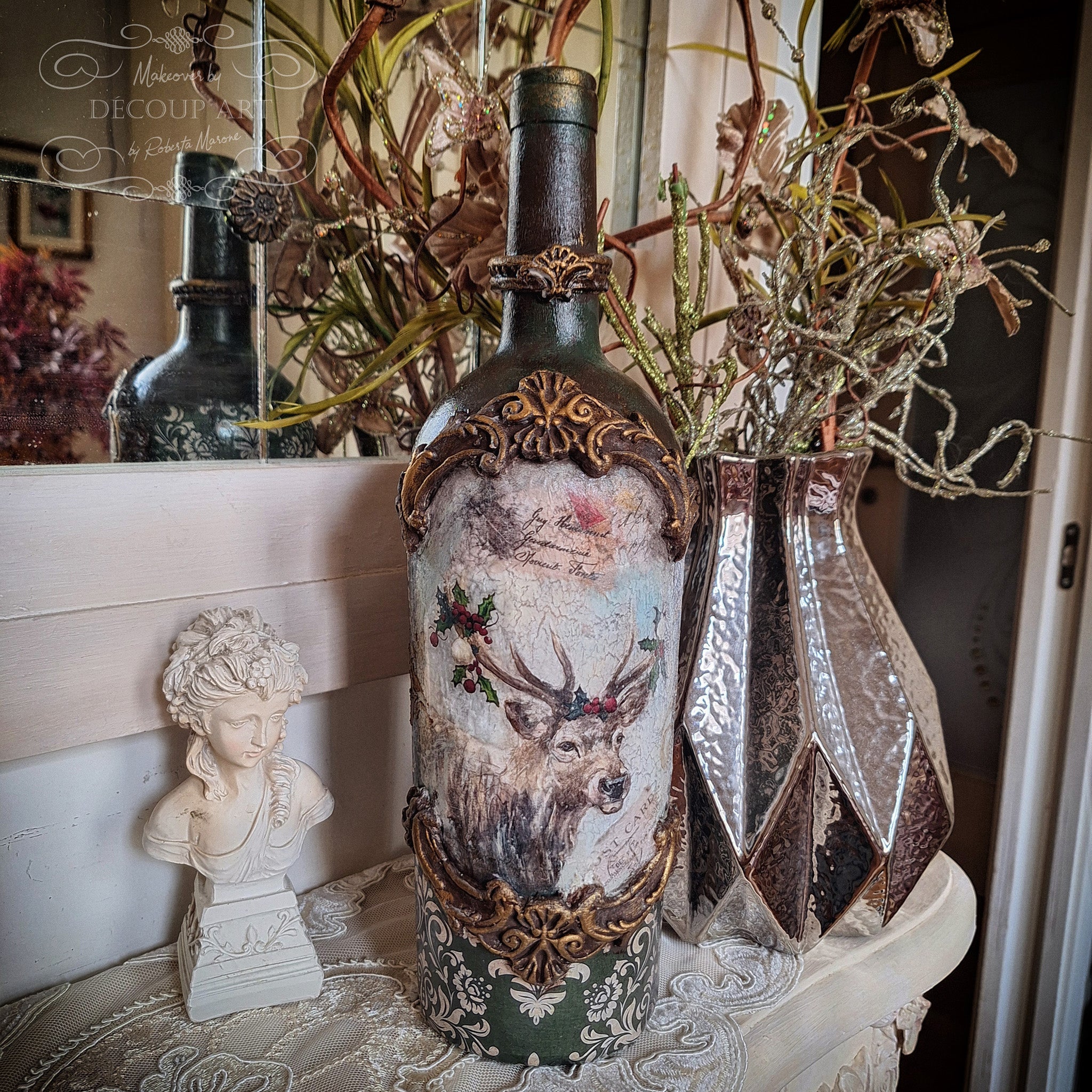 A wine bottle refurbished into a decor piece features Decoupage Queen's Snowy Elk rice paper in the center and Decoupage Queen's Green Christmas Damask rice paper on the bottom.