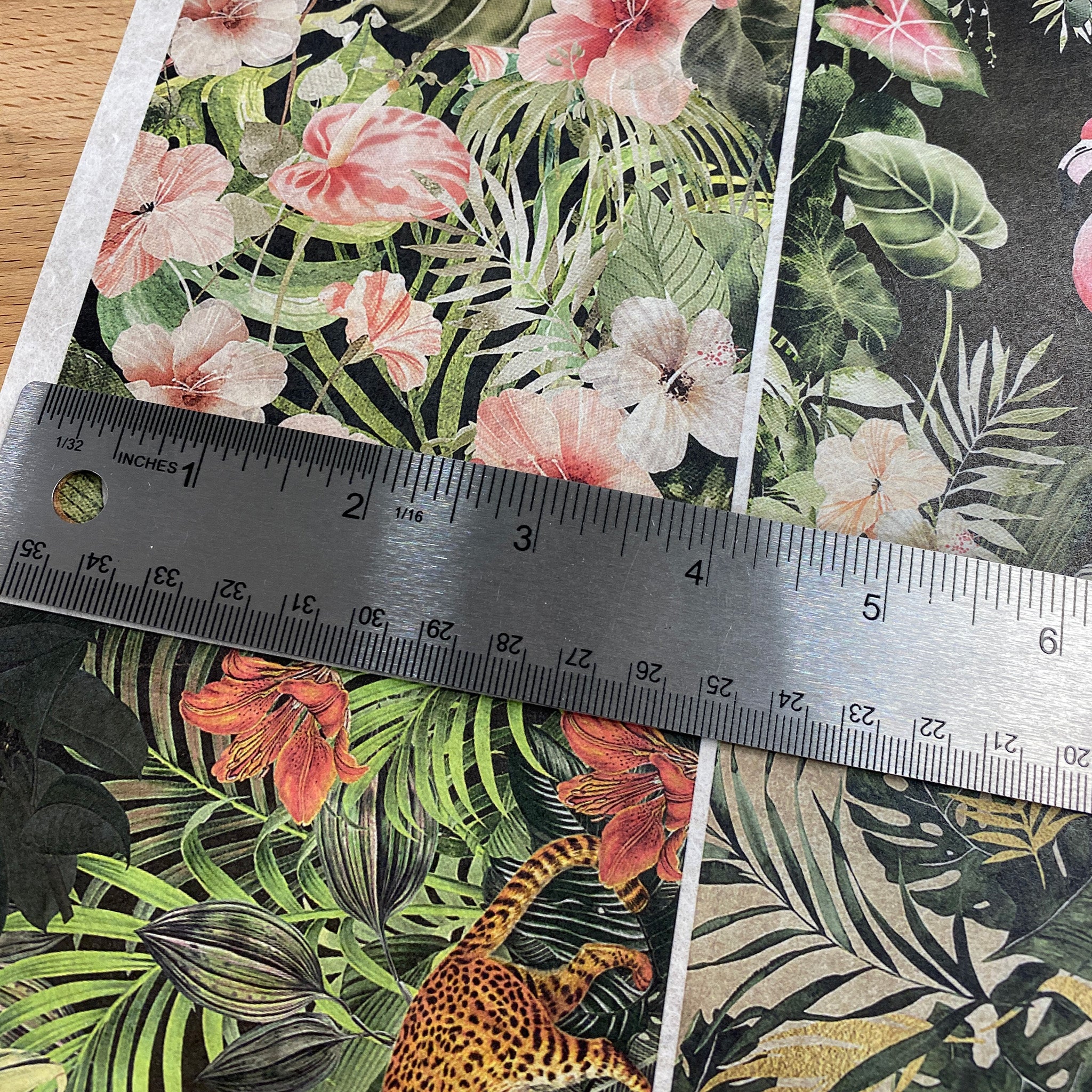 Decoupage Queen's Four Tropical Scenes A4 rice paper is shown against a wood background. A silver ruler on the paper shows a measurement of 4.1" for the length of one of the designs.