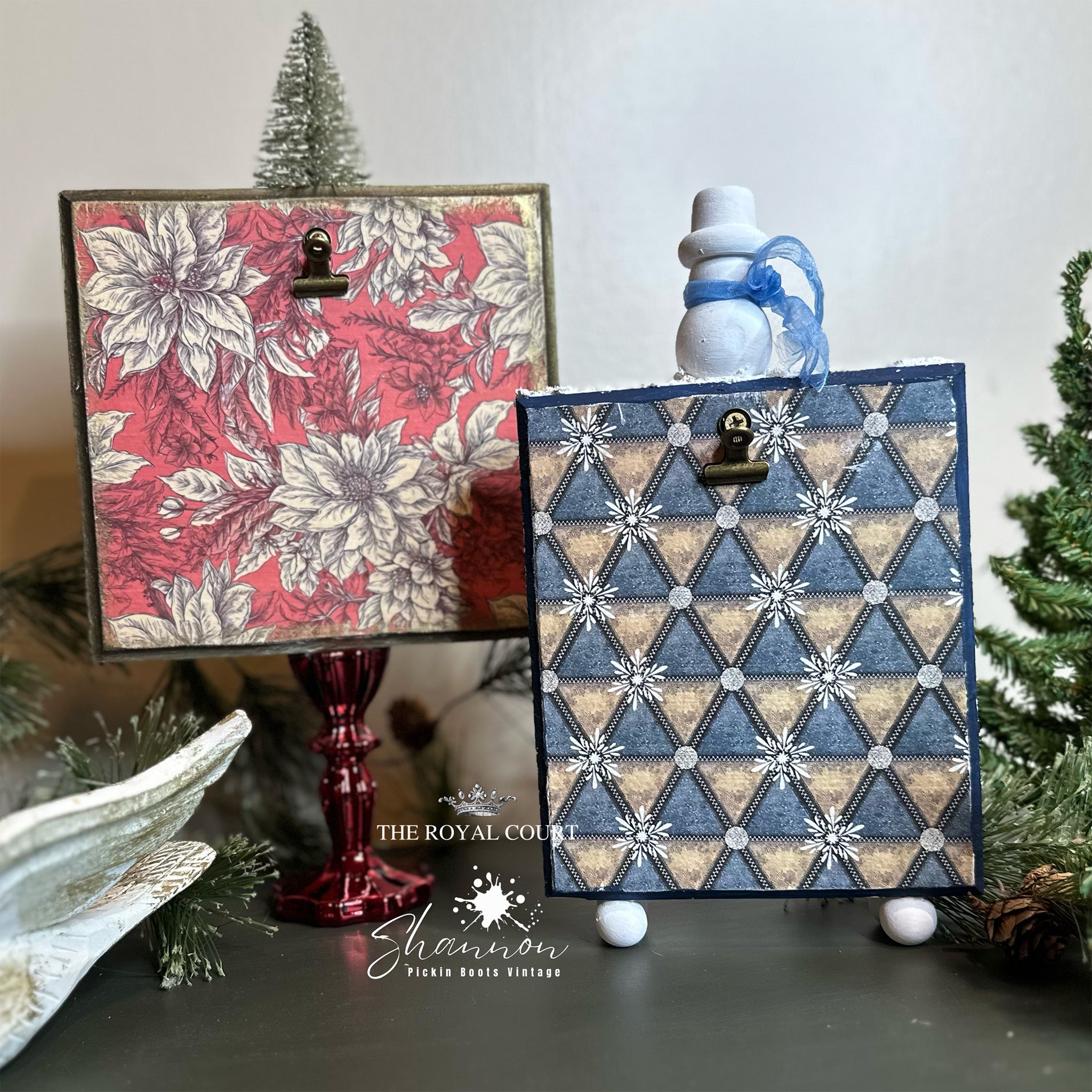 Two crafts that hold holiday greeting cards are set up on a table. Both crafts feature Decoupage Queen's Vintage Poinsettia and Geometric Winter rice papers on them.