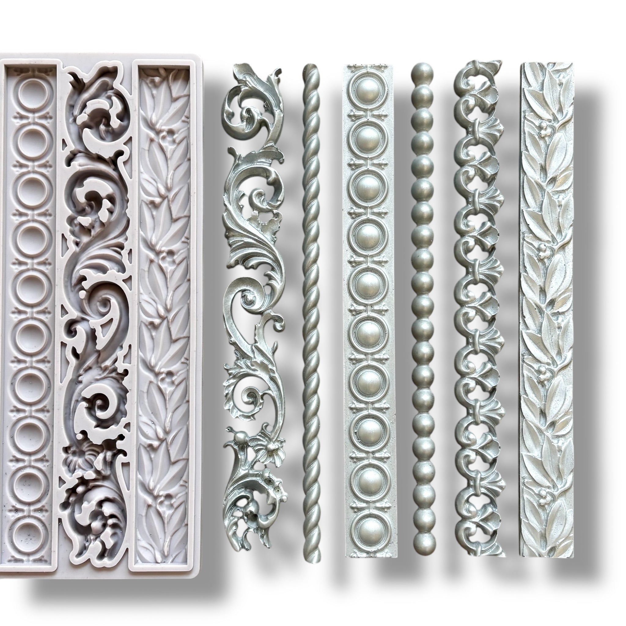 A light grey silicone mold and silver colored castings of 6 intricate border designs are against a white background.