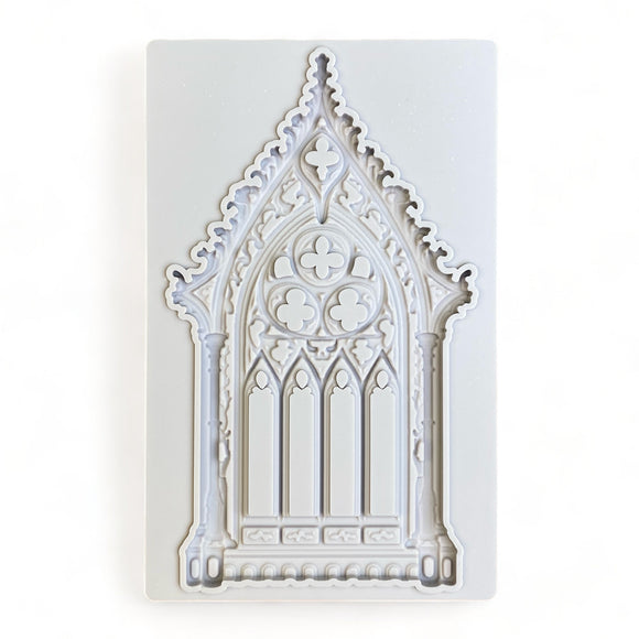 A light grey silicone mold of an ornate Gothic window is against a white background.