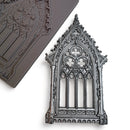 A brown silicone mold and silver colored casting of an ornate Gothic window are against a white background.